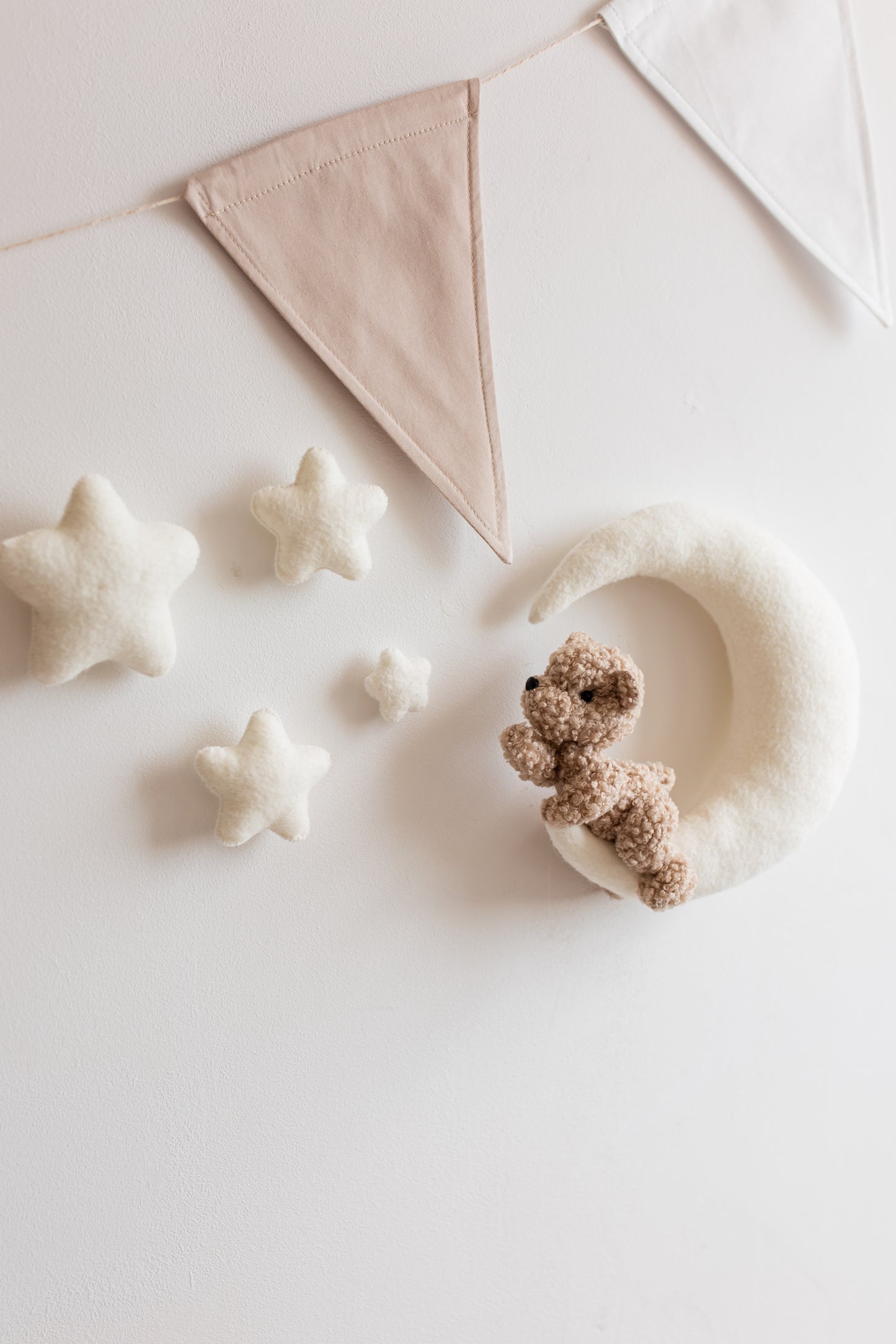 Small teddy bear and star-shaped objects on a light surface with a decorative flag in the background.
