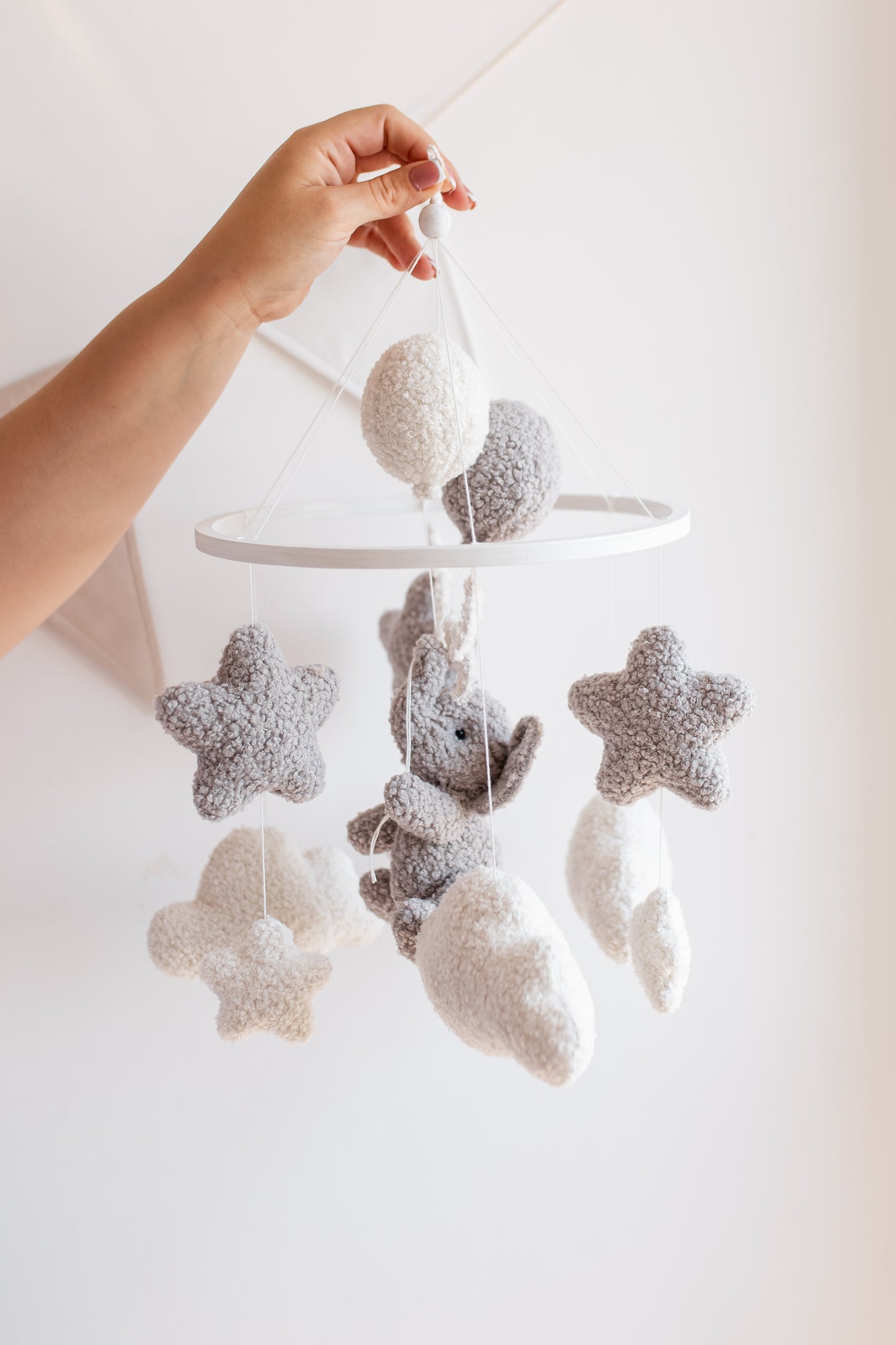Baby mobile with stars and a bear hanging from a white rod against a light background