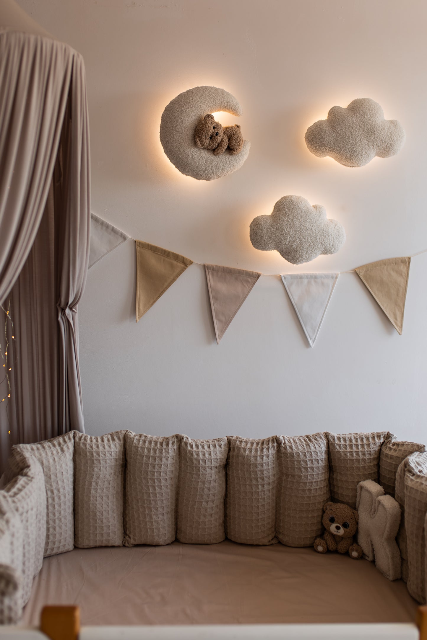 Children's room with cloud-shaped wall lights and a teddy bear.