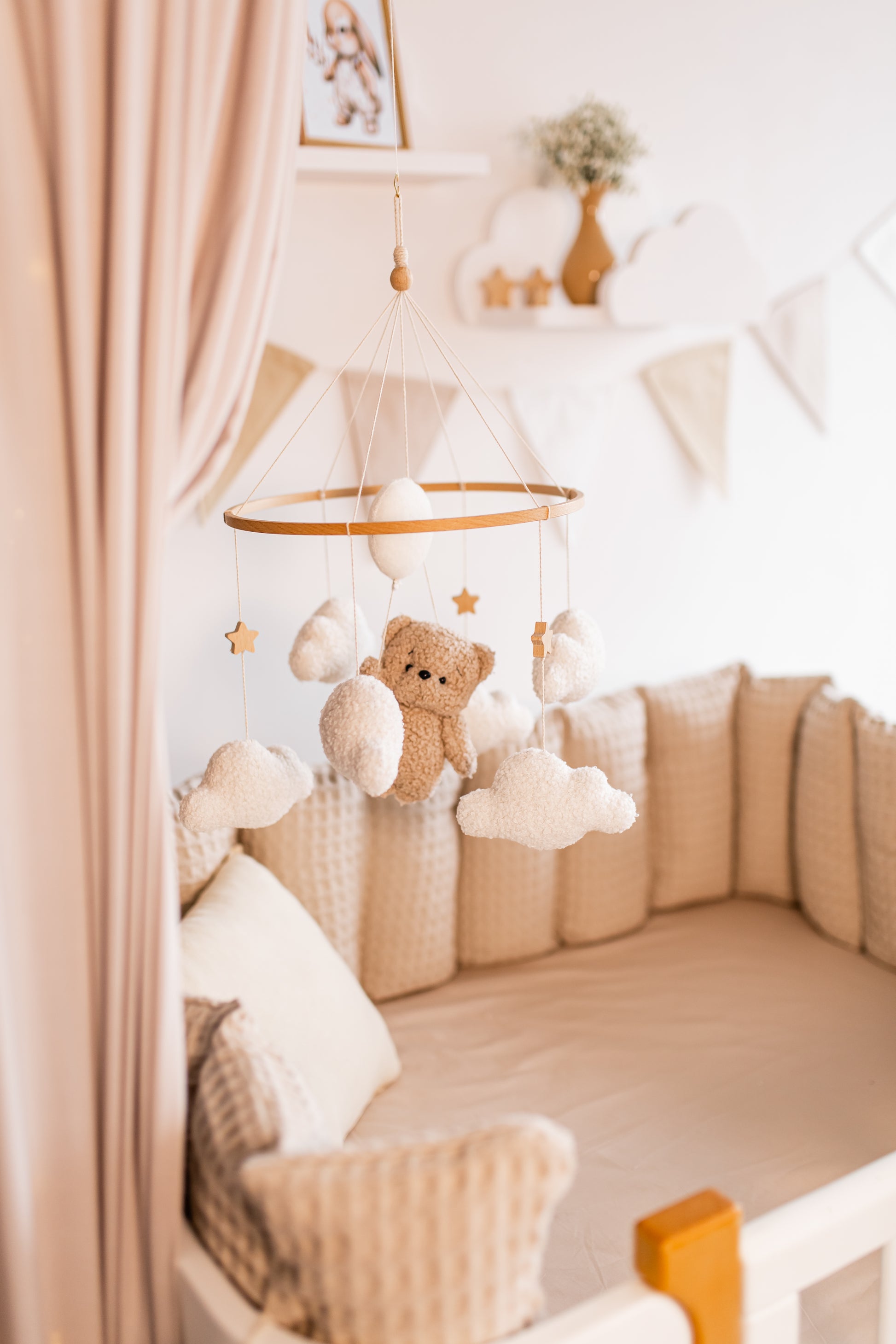 Children's crib with teddy bear and cloud mobile in a nursery setting