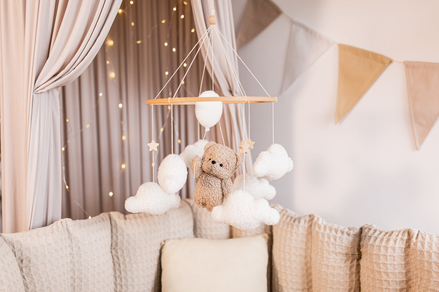 Baby mobile with teddy bear hanging above a crib in a nursery.