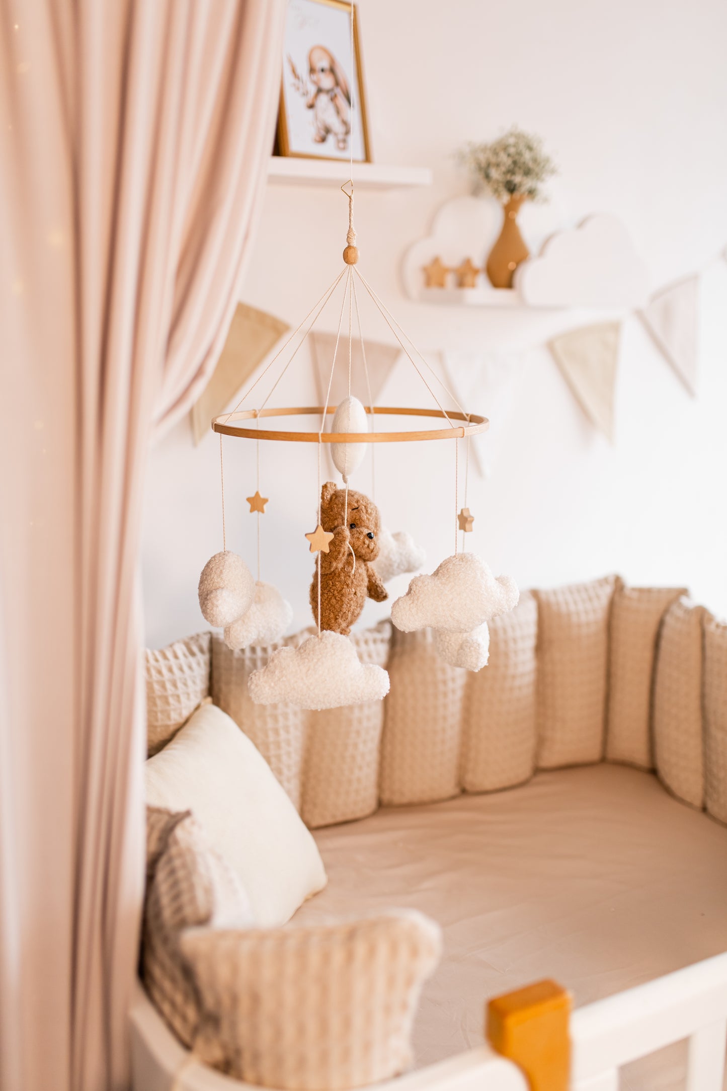 Children's crib with canopy, teddy bear baby mobile and decorative items in a nursery setting.