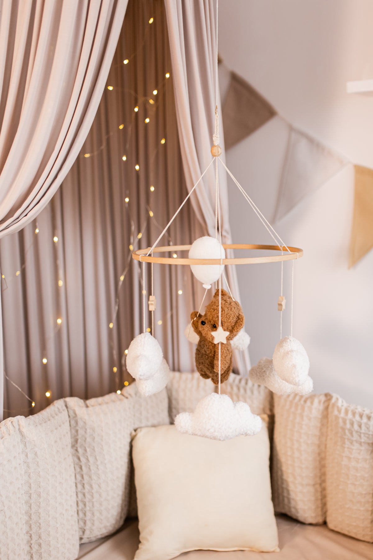 Baby crib mobile with teddy bear and balloons hanging above a crib with soft bedding.