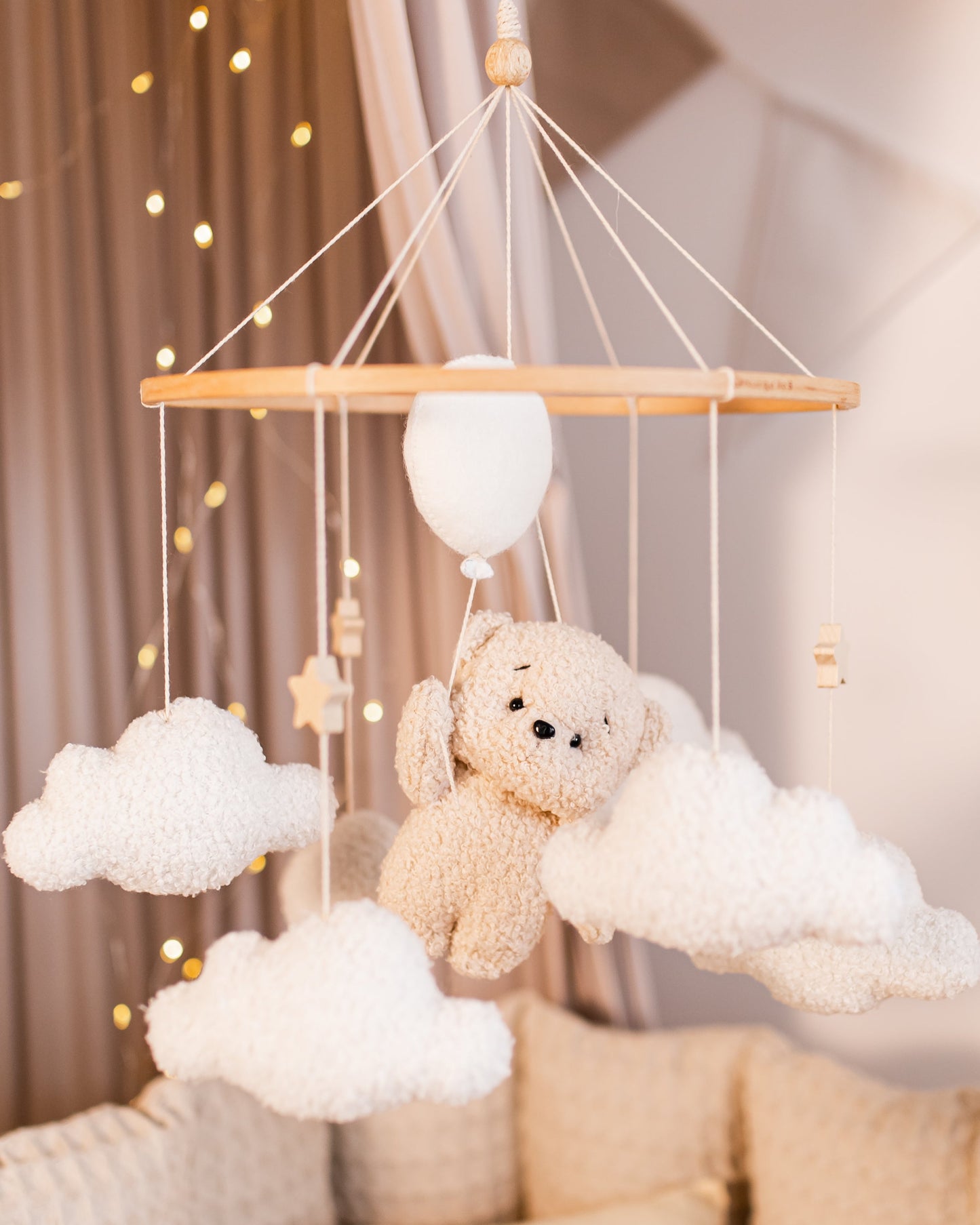 Boucle bear baby mobile floating on balloons and clouds above crib