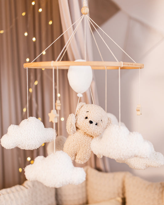 Boucle bear baby mobile floating on balloons and clouds above crib