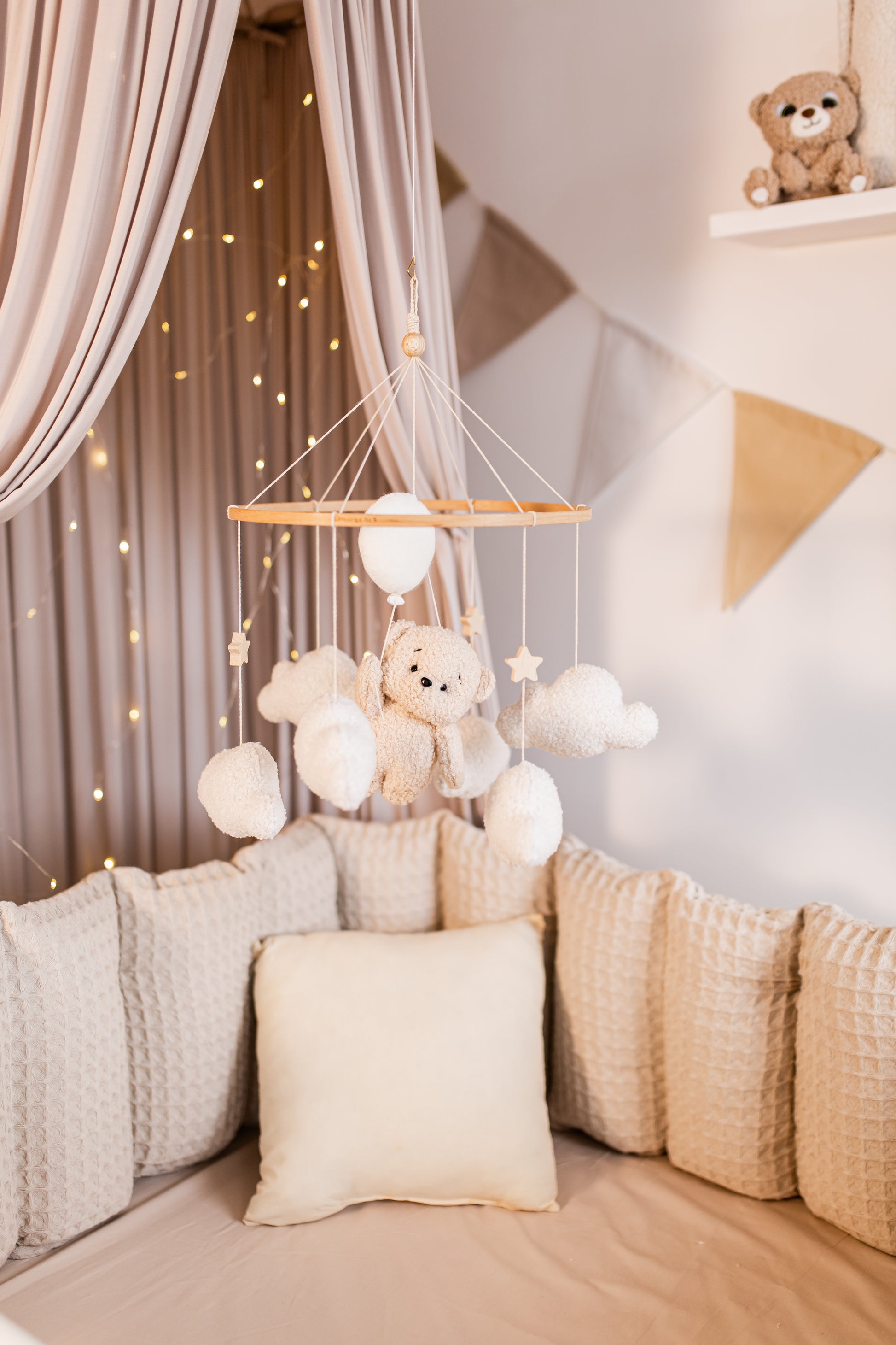 Children's room with teddy bear-themed baby mobile and soft pillows.