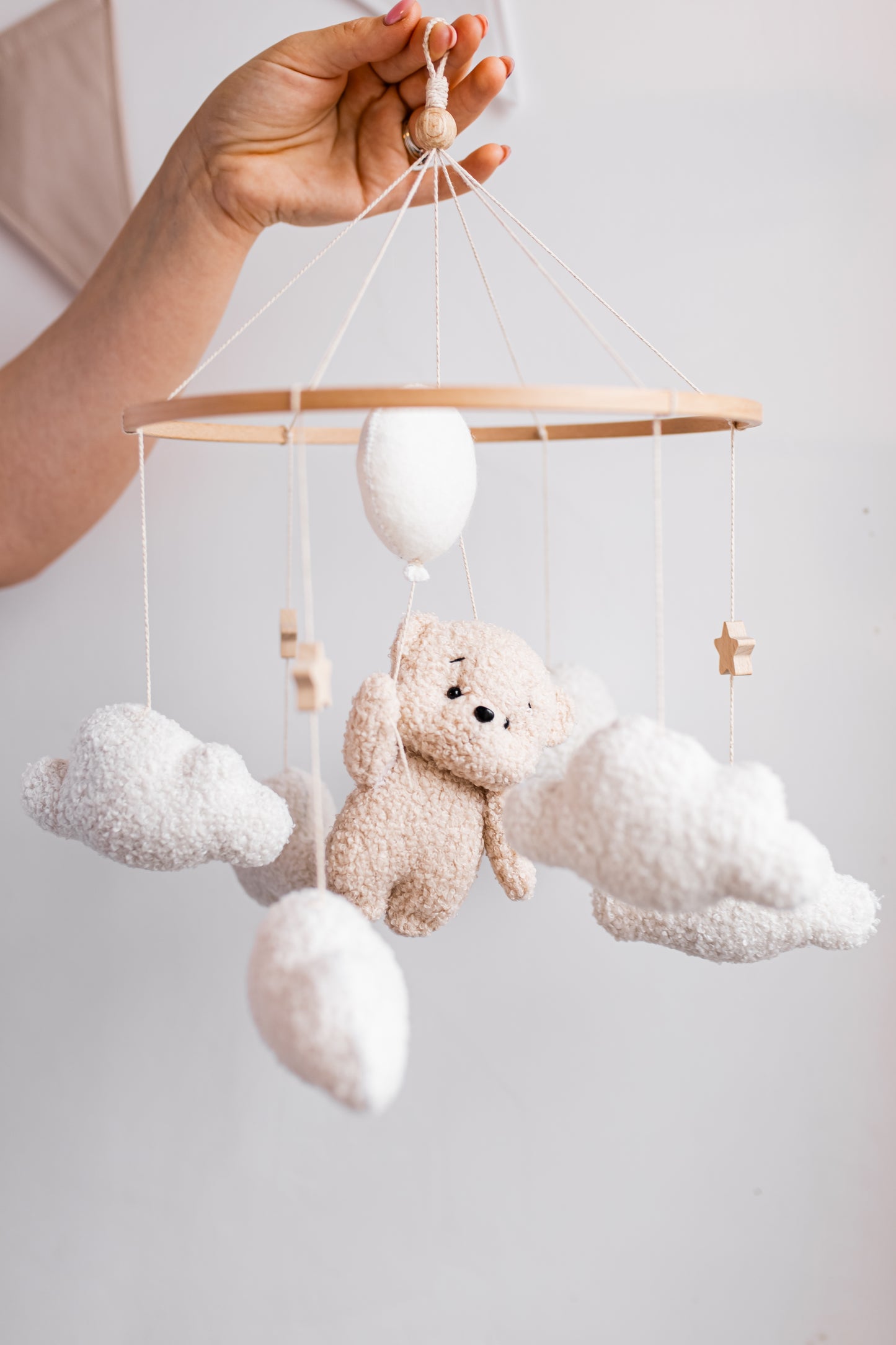 Baby mobile with teddy bear and clouds against a light background