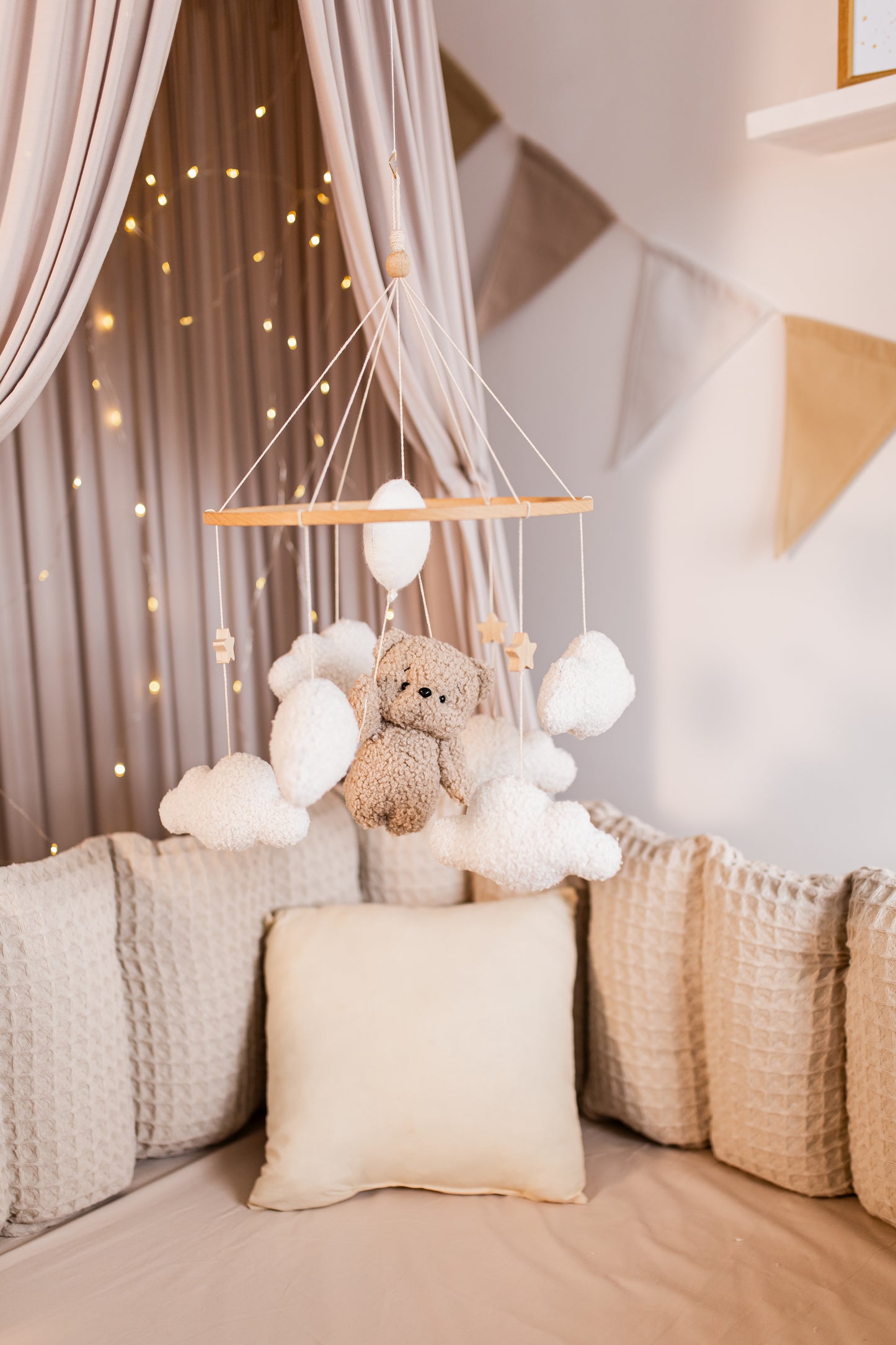 Baby crib mobile with teddy bear and balloons hanging above a crib with soft bedding.