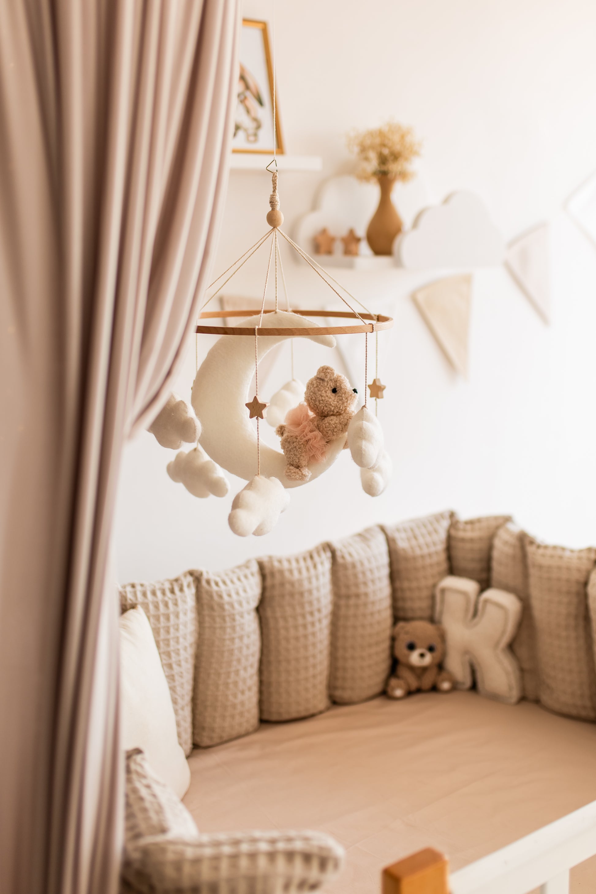 Nursery room with a crib, teddy bear, and hanging baby mobile.