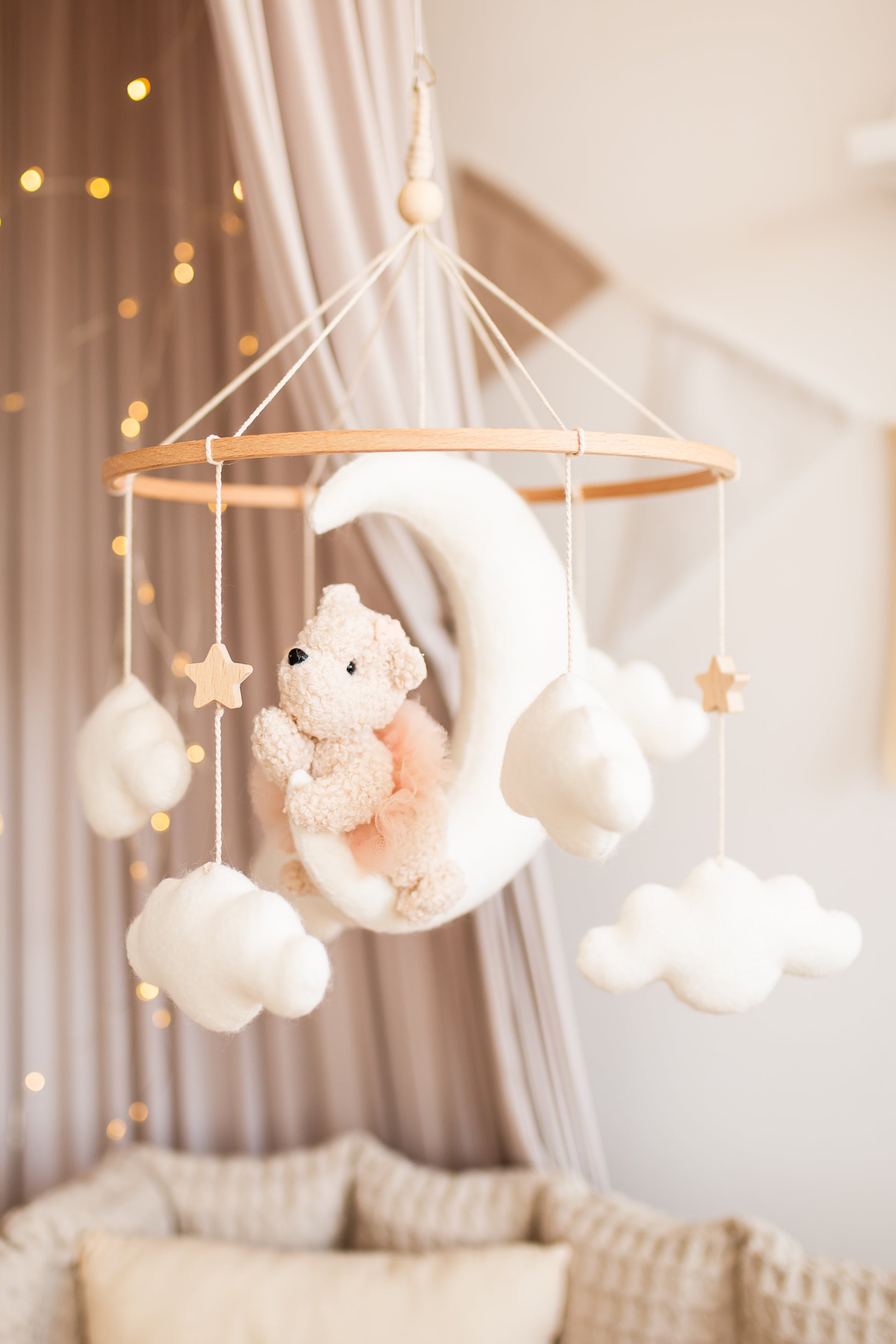 Baby mobile with girl teddy bear and stars hanging above a crib