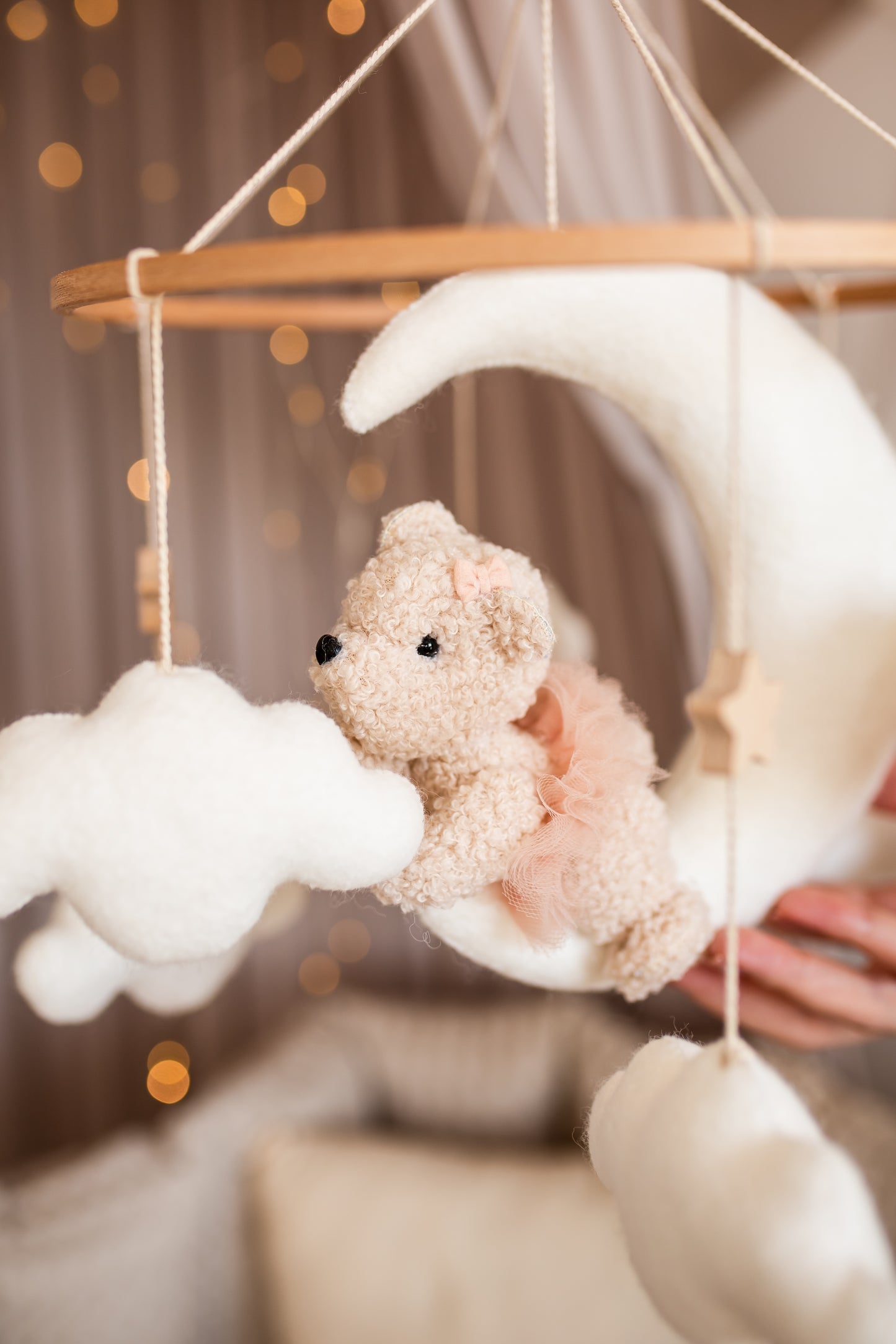 Baby mobile with teddy bear, clouds, and crescent moon against a blurred background