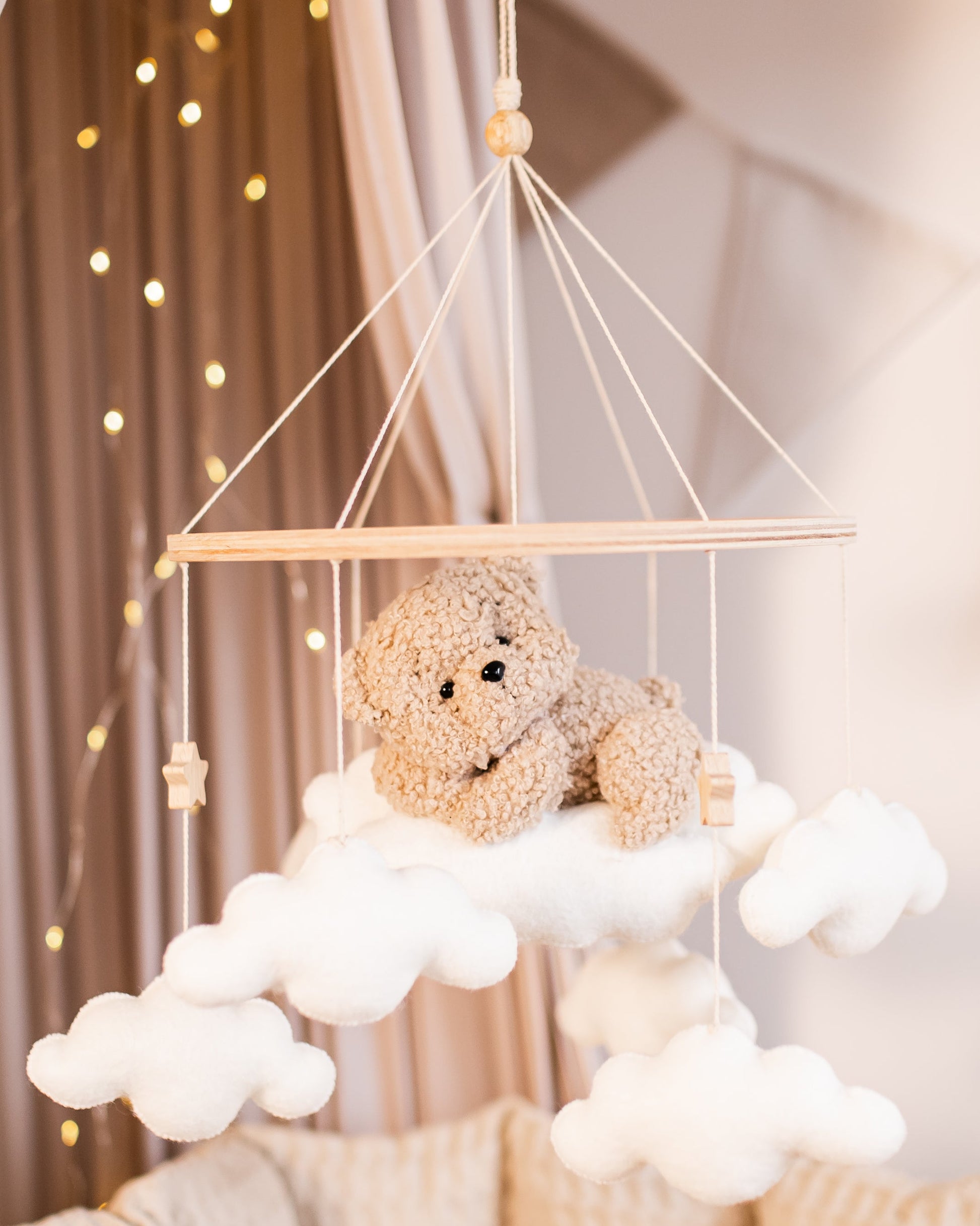 Boucle teddy bear mobile on cloud hanging above crib in neutral tones