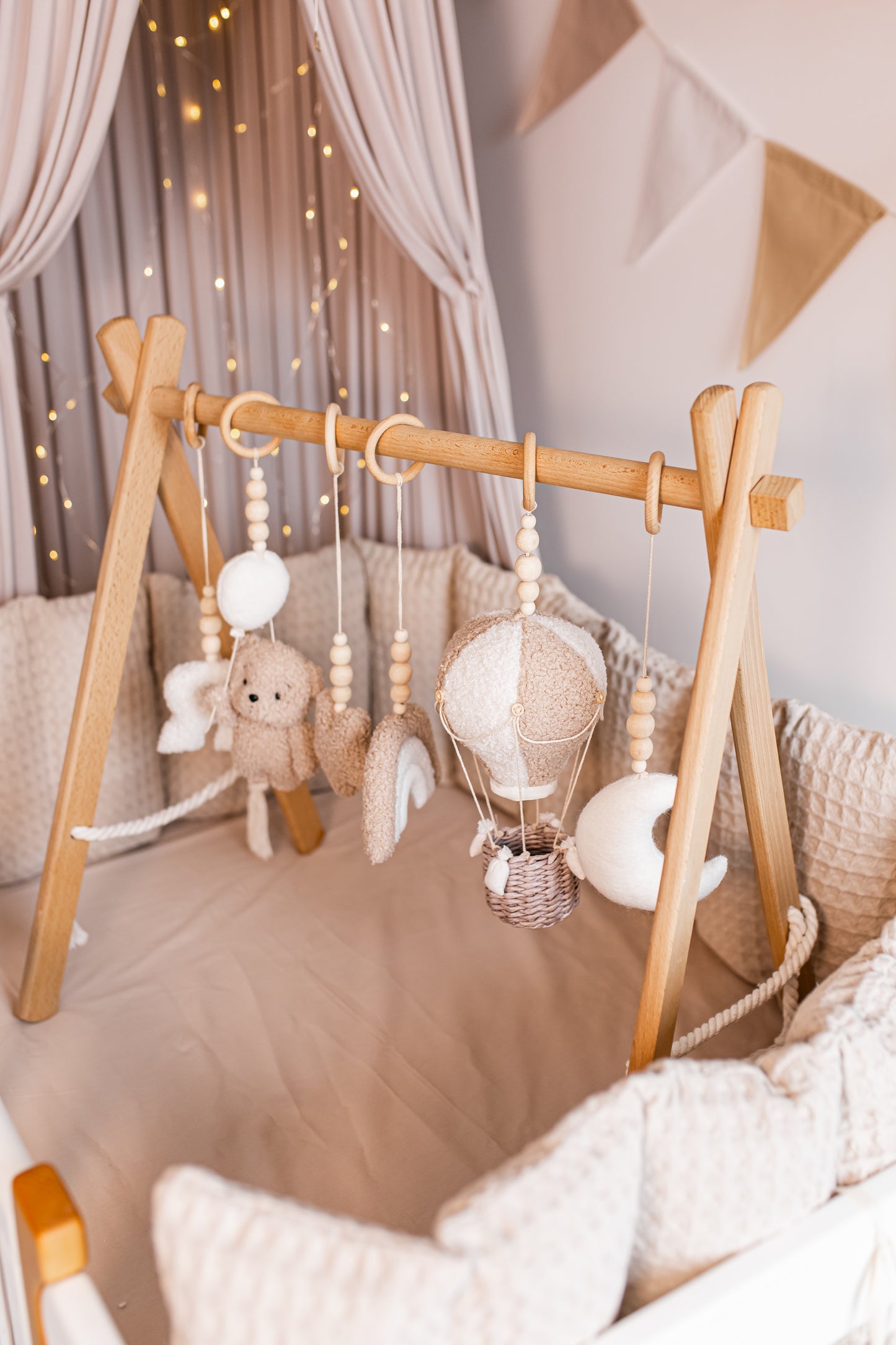 Wooden crib with hanging baby gym in a nursery setting