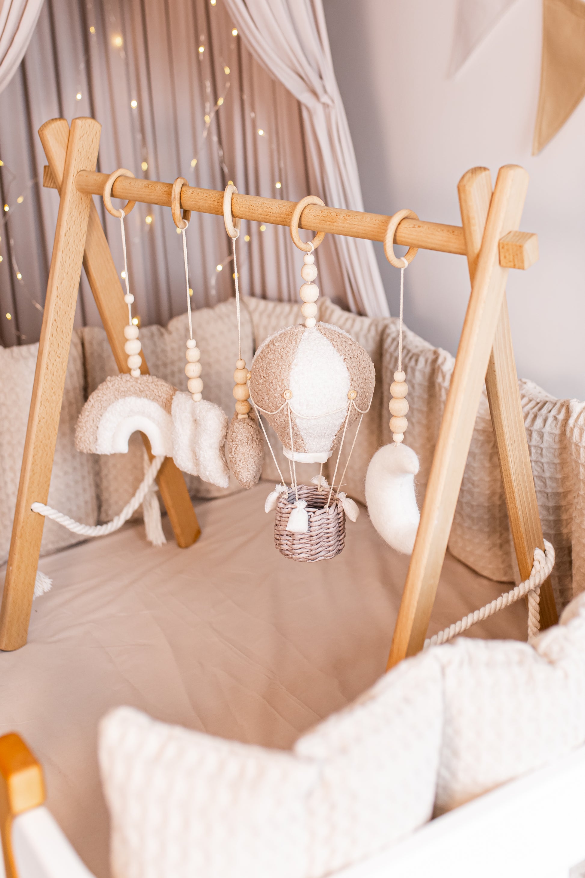 Wooden baby gym with hanging boucle toys in a nursery setting