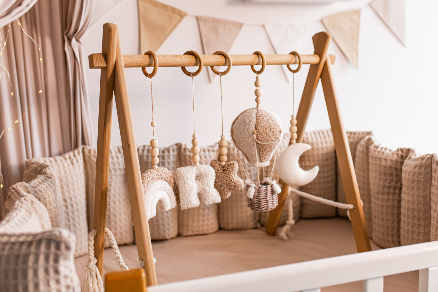 Wooden crib with hanging baby toys and baby gym in a nursery setting