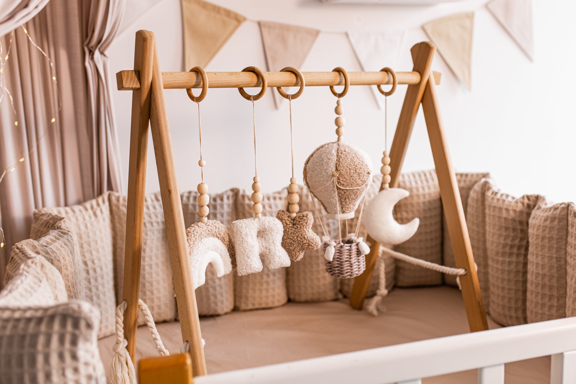Wooden crib with hanging baby toys and baby gym in a nursery setting