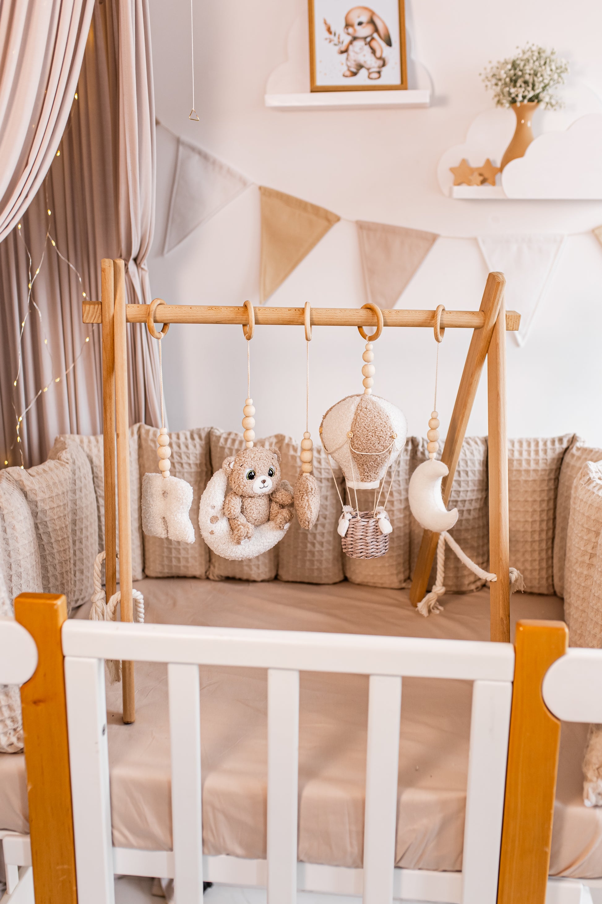 Baby crib with wooden cribbage and hanging toys baby gym in a nursery setting.