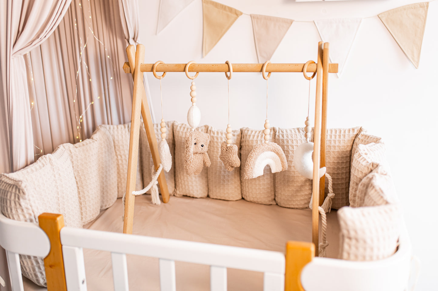 Children's play gym with wooden frame and soft pillows in a neutral-colored room.