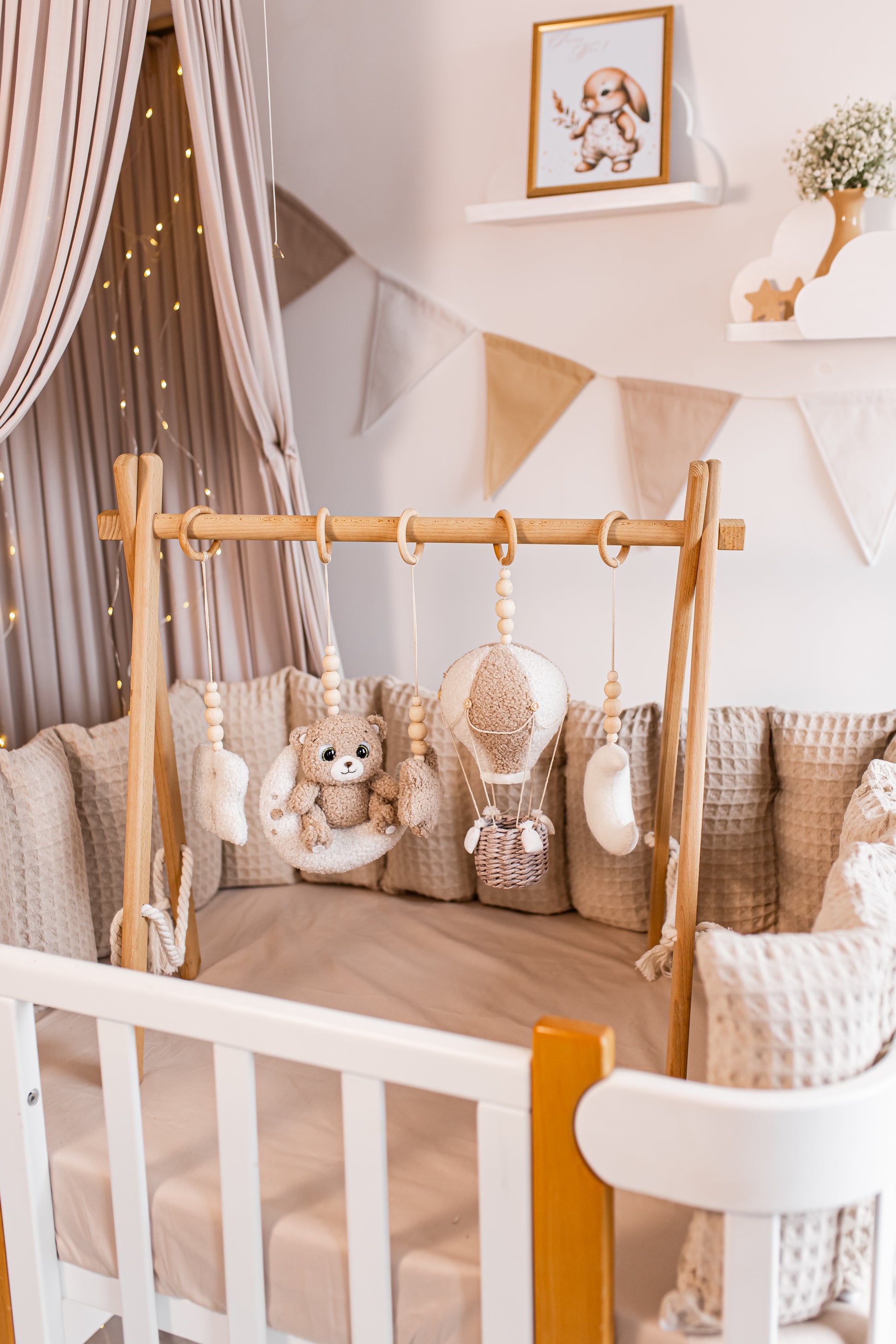 Nursery room with wooden crib, teddy bear, baby gym and decorative elements.