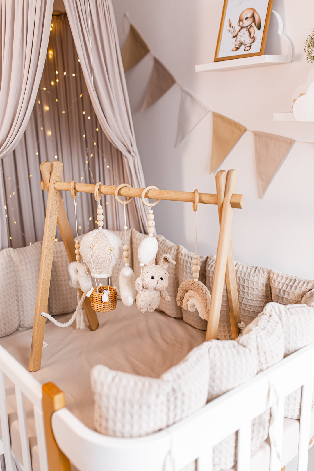 Nursery room with wooden crib, plush toys, baby gym and decorative elements.