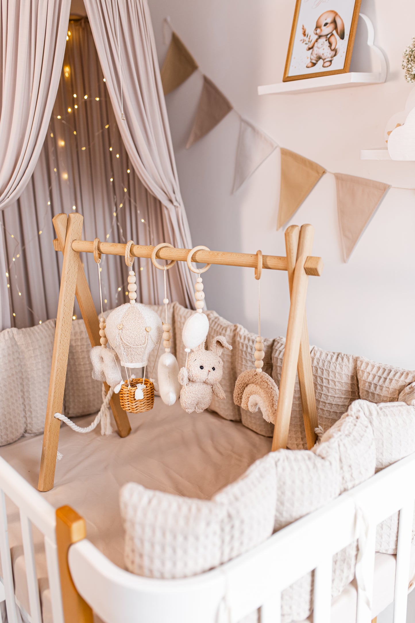 Nursery room with wooden crib, plush toys, baby gym and decorative elements.
