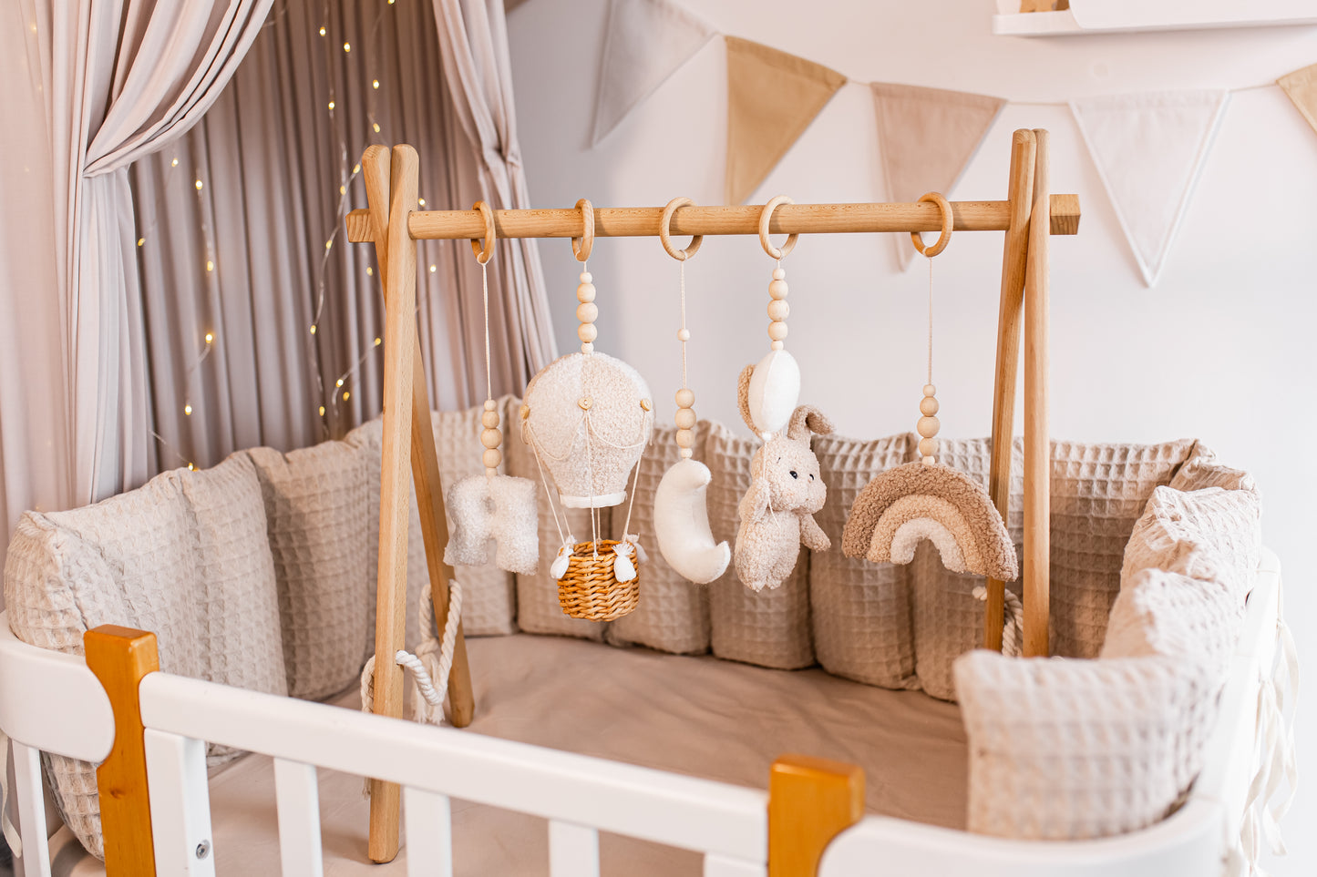Baby crib with wooden baby gym and decorative elements in a cozy nursery.