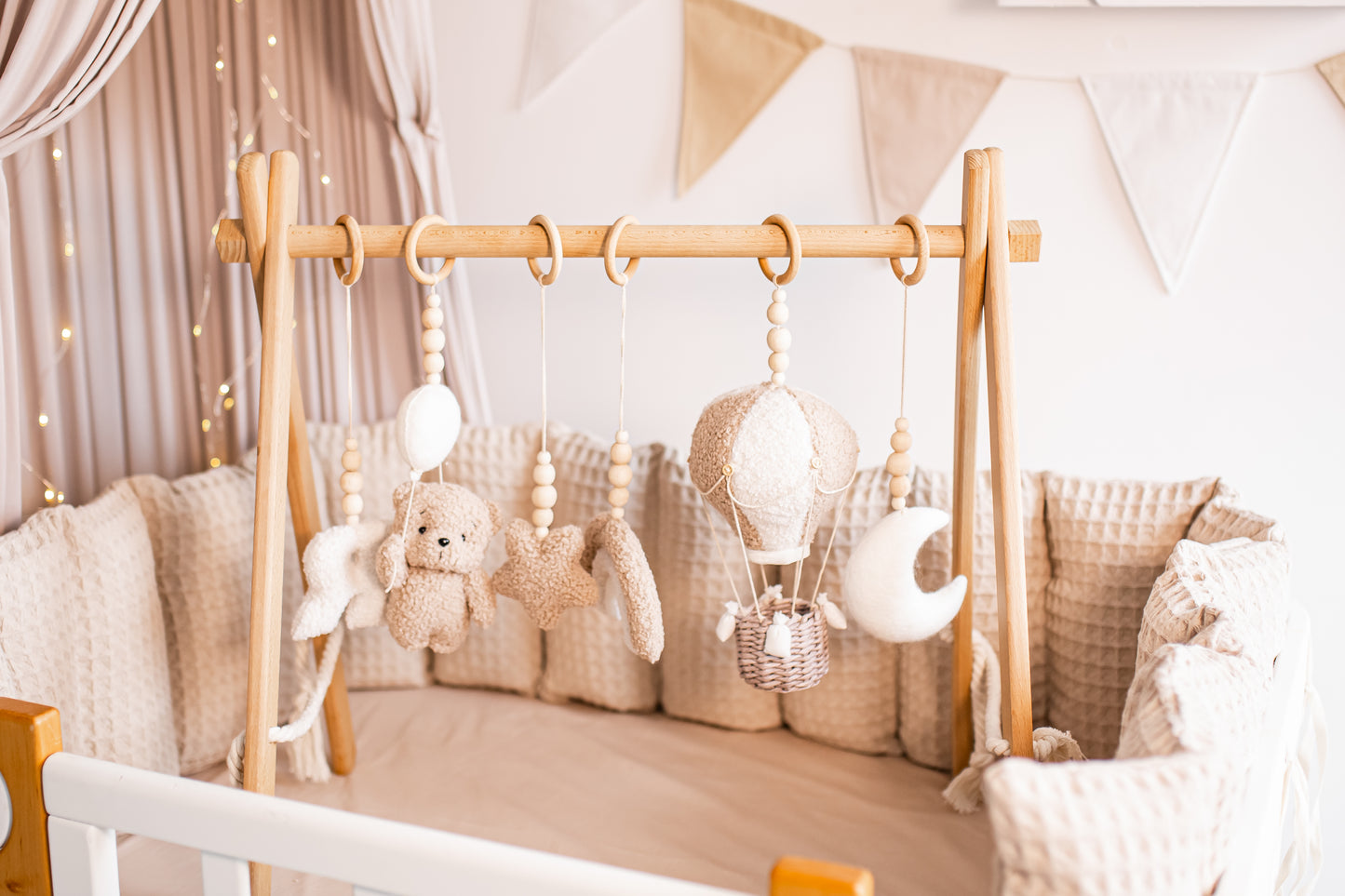 Baby crib with wooden baby gym and decorative pillows in a nursery setting.