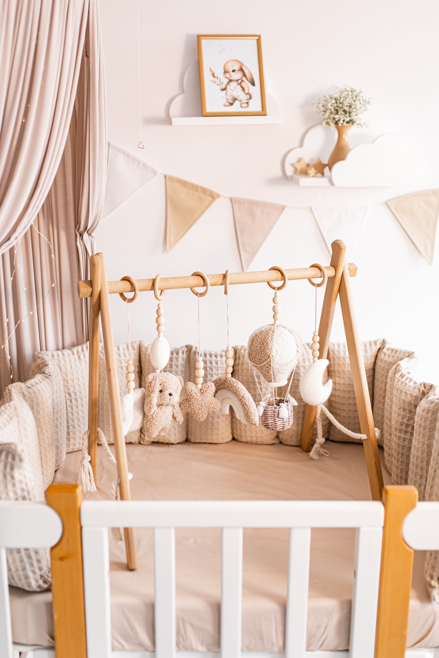 Nursery room with wooden crib, baby gym, stuffed animals, and decorative elements.