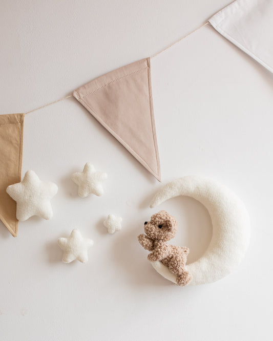 Bouclé bear on crescent moon wall décor with clouds and stars above baby crib