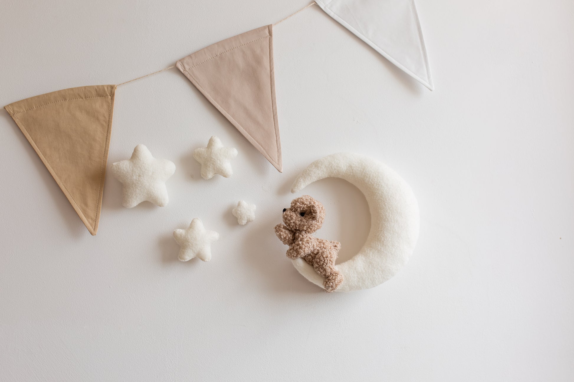 Decorative items including a moon with a teddy bear, star-shaped objects on a light background.