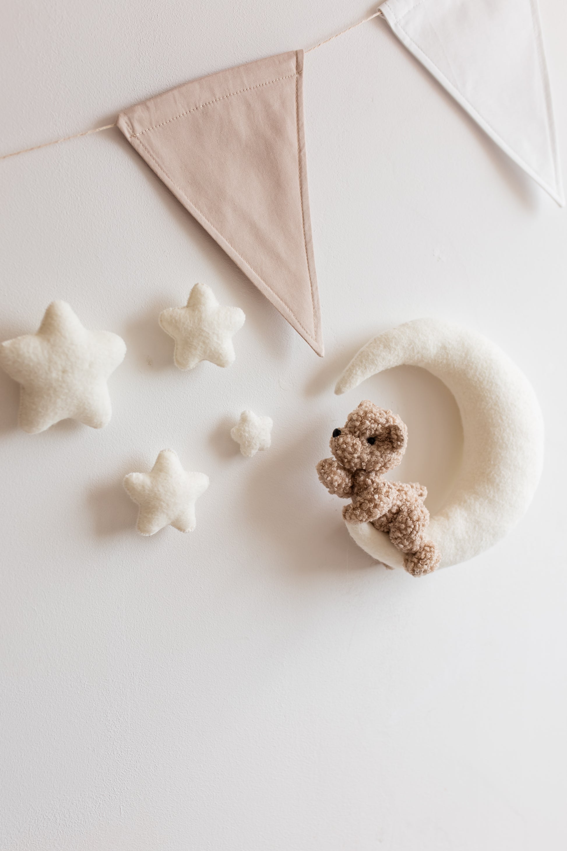 Small teddy bear and star-shaped objects on a light surface with a decorative flag in the background.