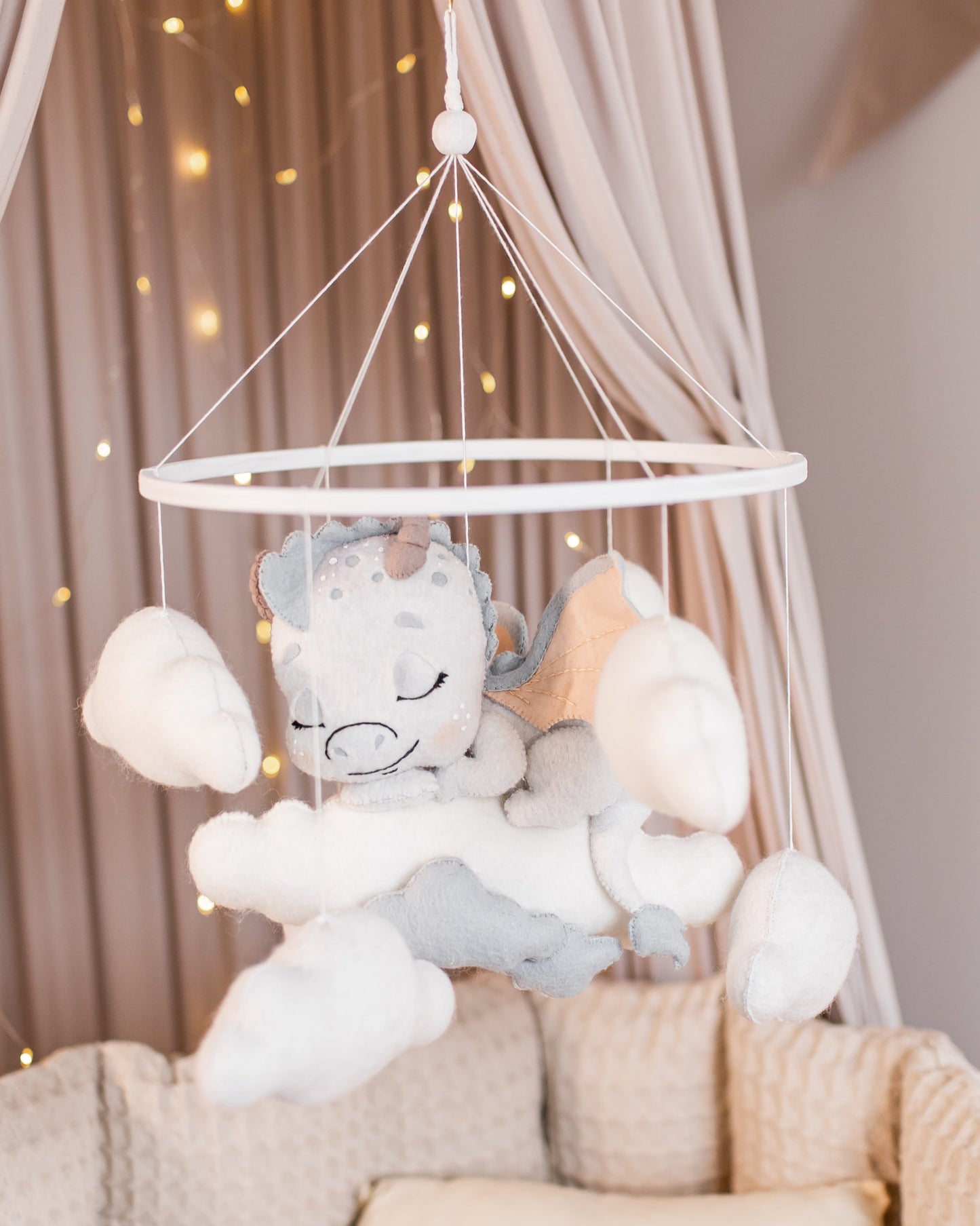 Boucle dragon baby mobile hanging above crib in soft fantasy tones