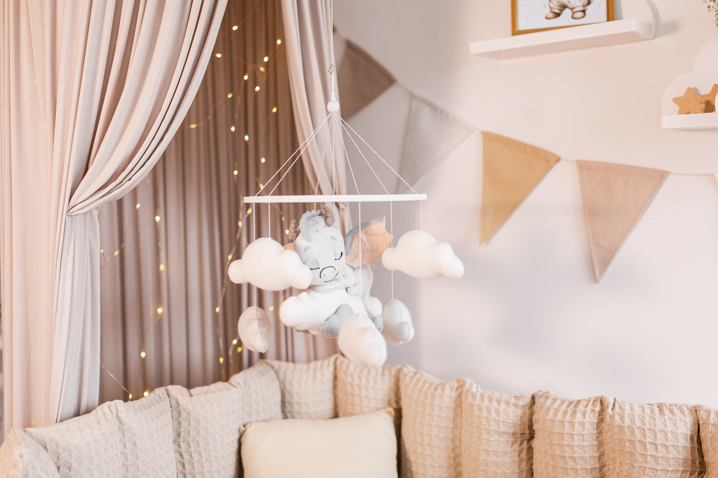 Baby mobile with dragon and clouds hanging above a crib in a nursery.