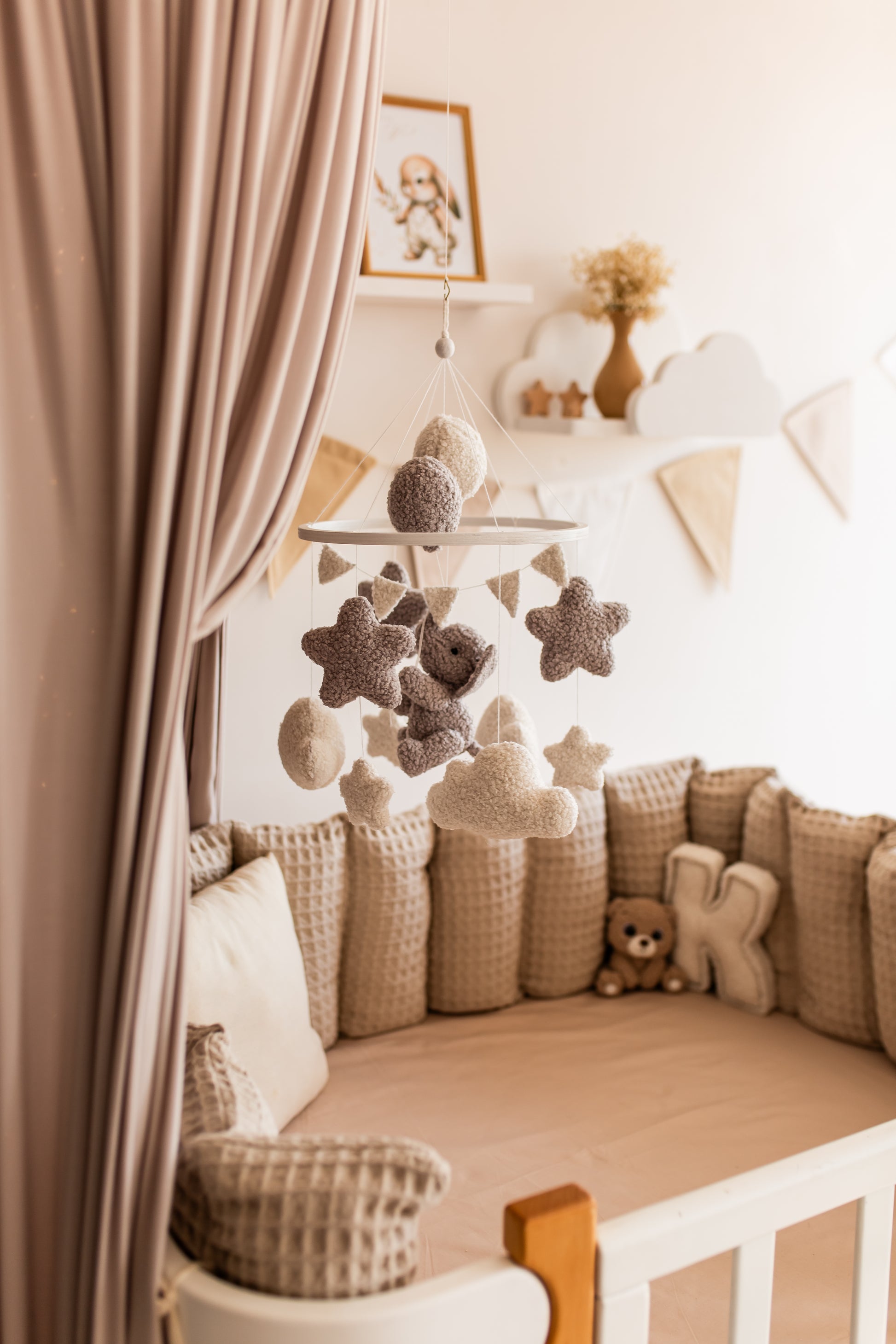 Nursery room with a crib, decorative pillows, and a star-shaped mobile.