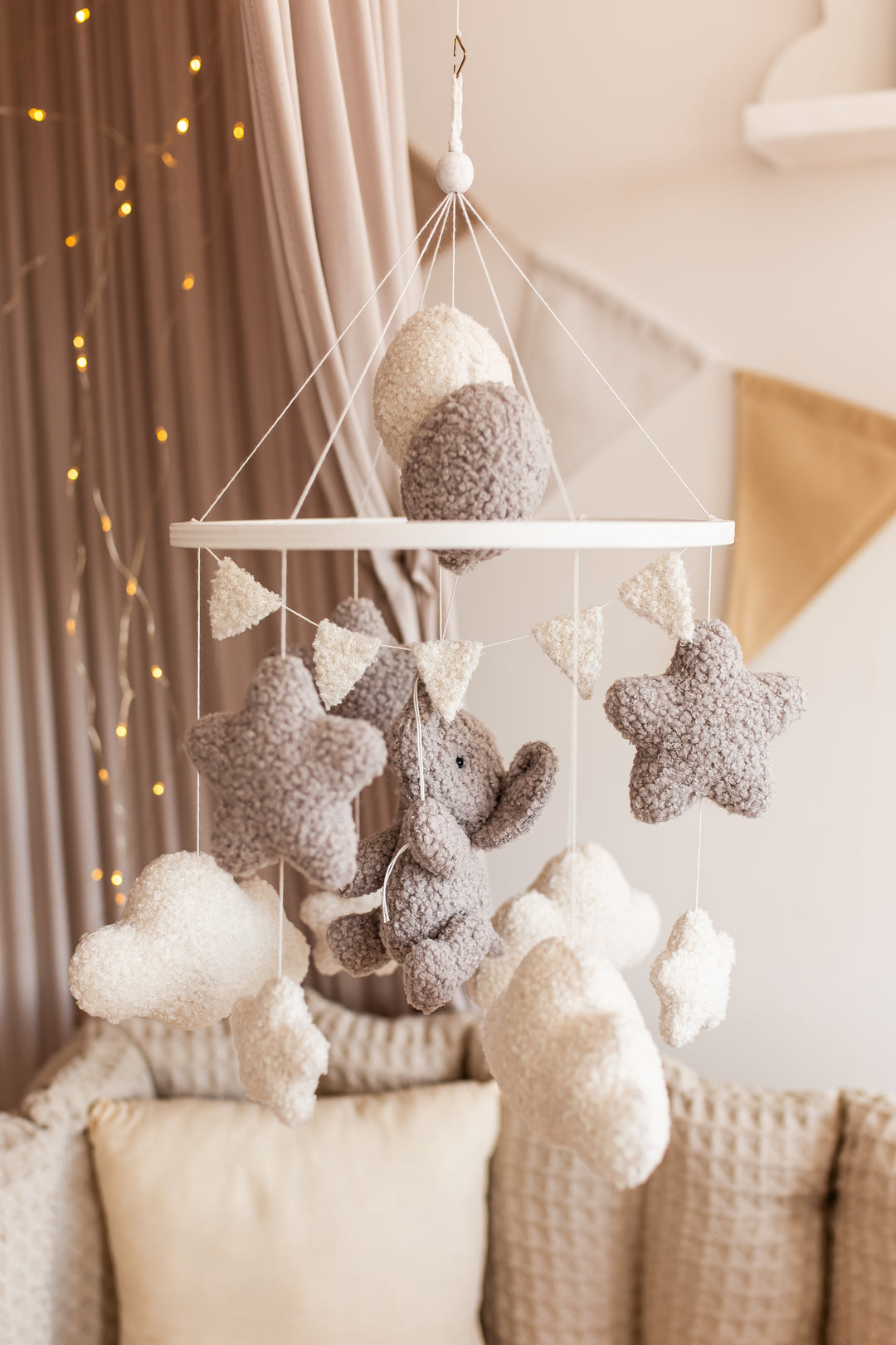 Decorative mobile with stars, clouds, and elephants hanging above a sofa.