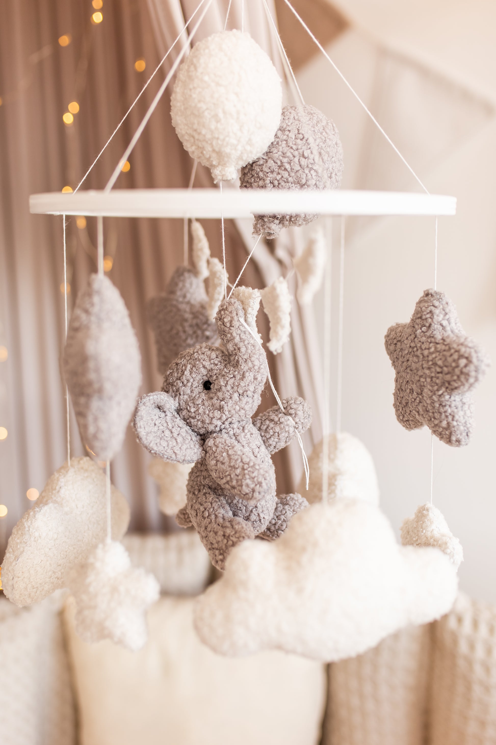 Decorative mobile with plush toys hanging against a neutral background