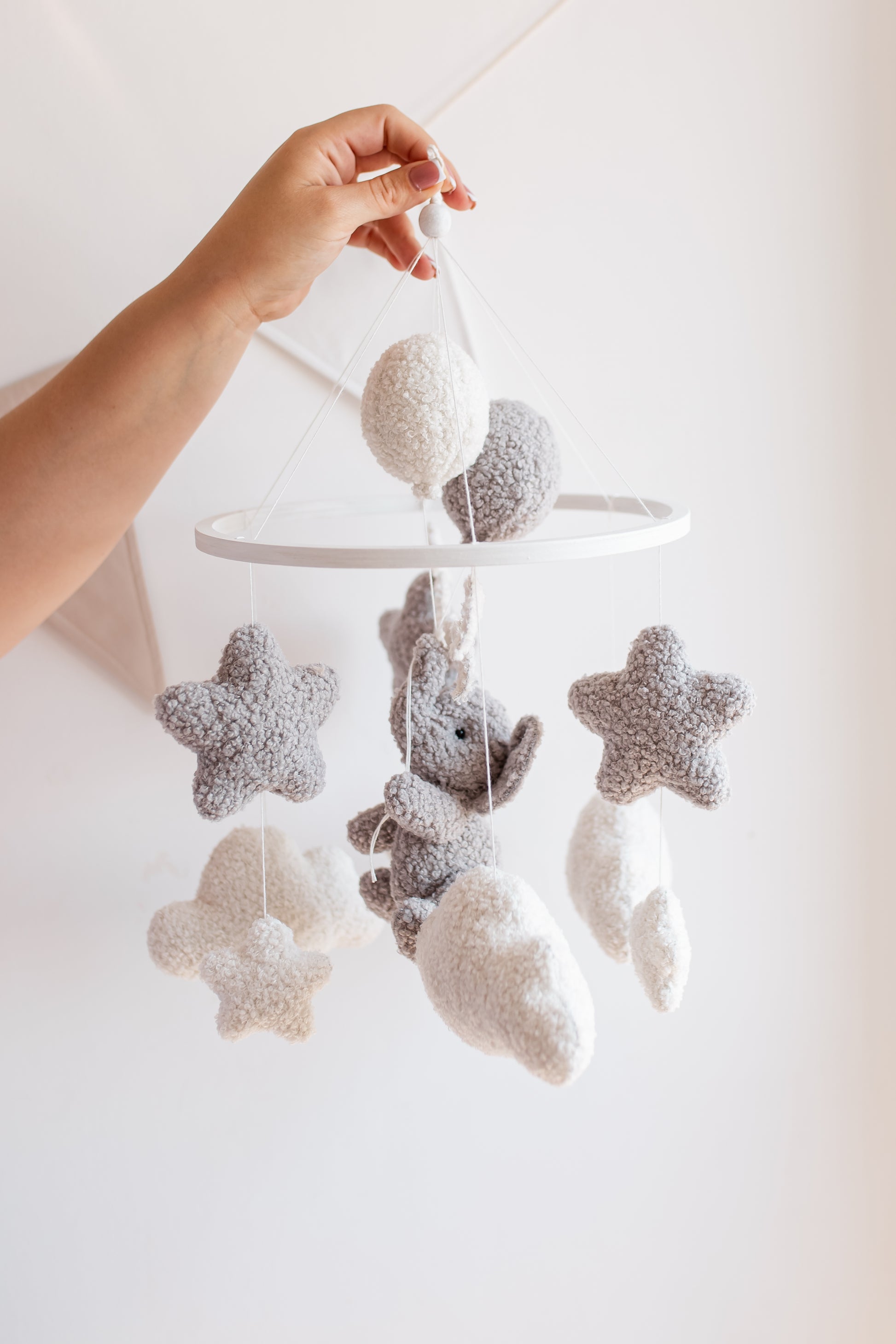 Baby mobile with stars and a bear hanging from a white rod against a light background