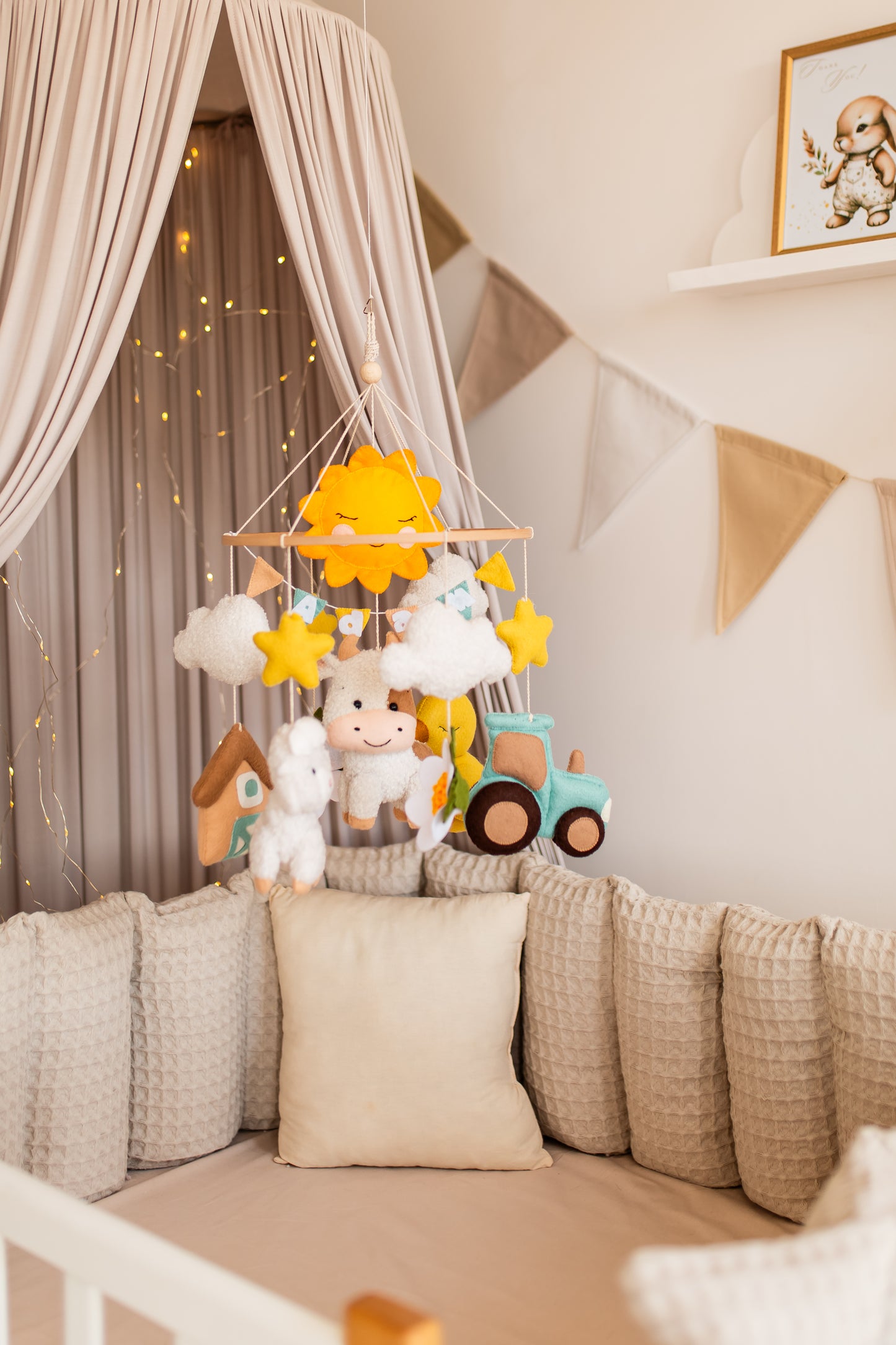 Children's crib with a hanging toy, soft pillows, and decorative elements in a nursery.