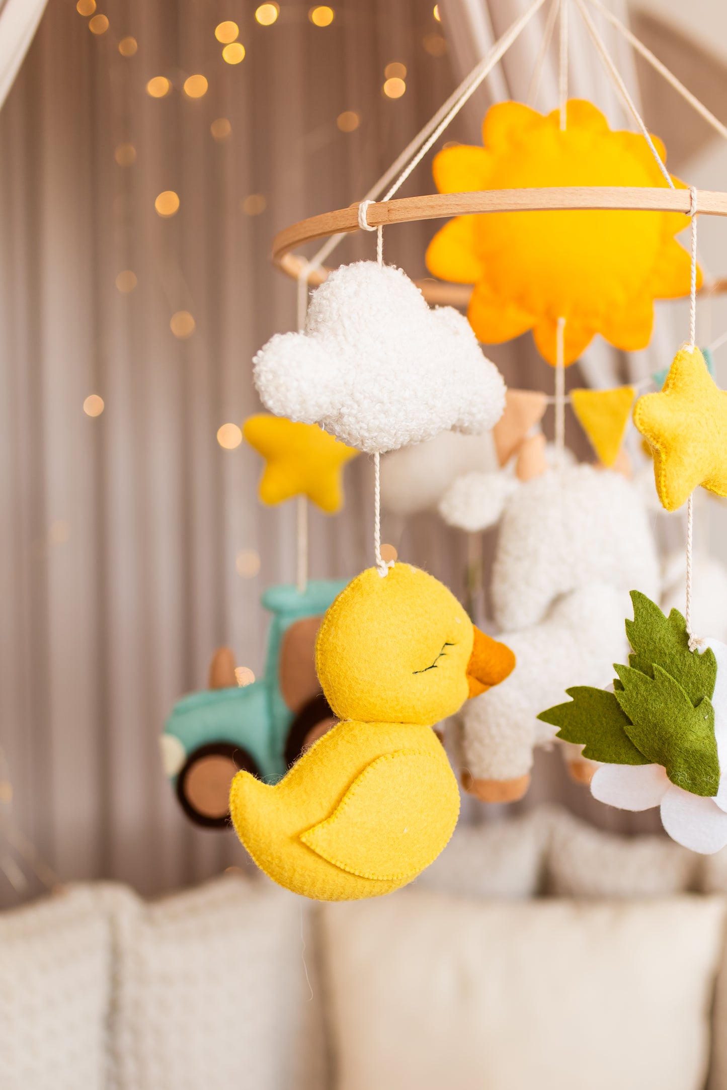Baby mobile with yellow duck, stars, and clouds hanging against a blurred background
