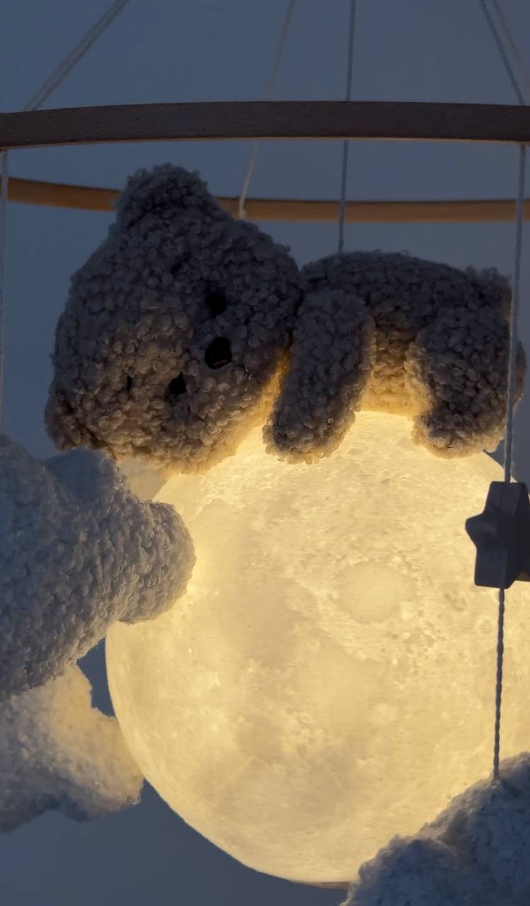 Bear baby mobile with a glowing moon-like ball under a blue sky