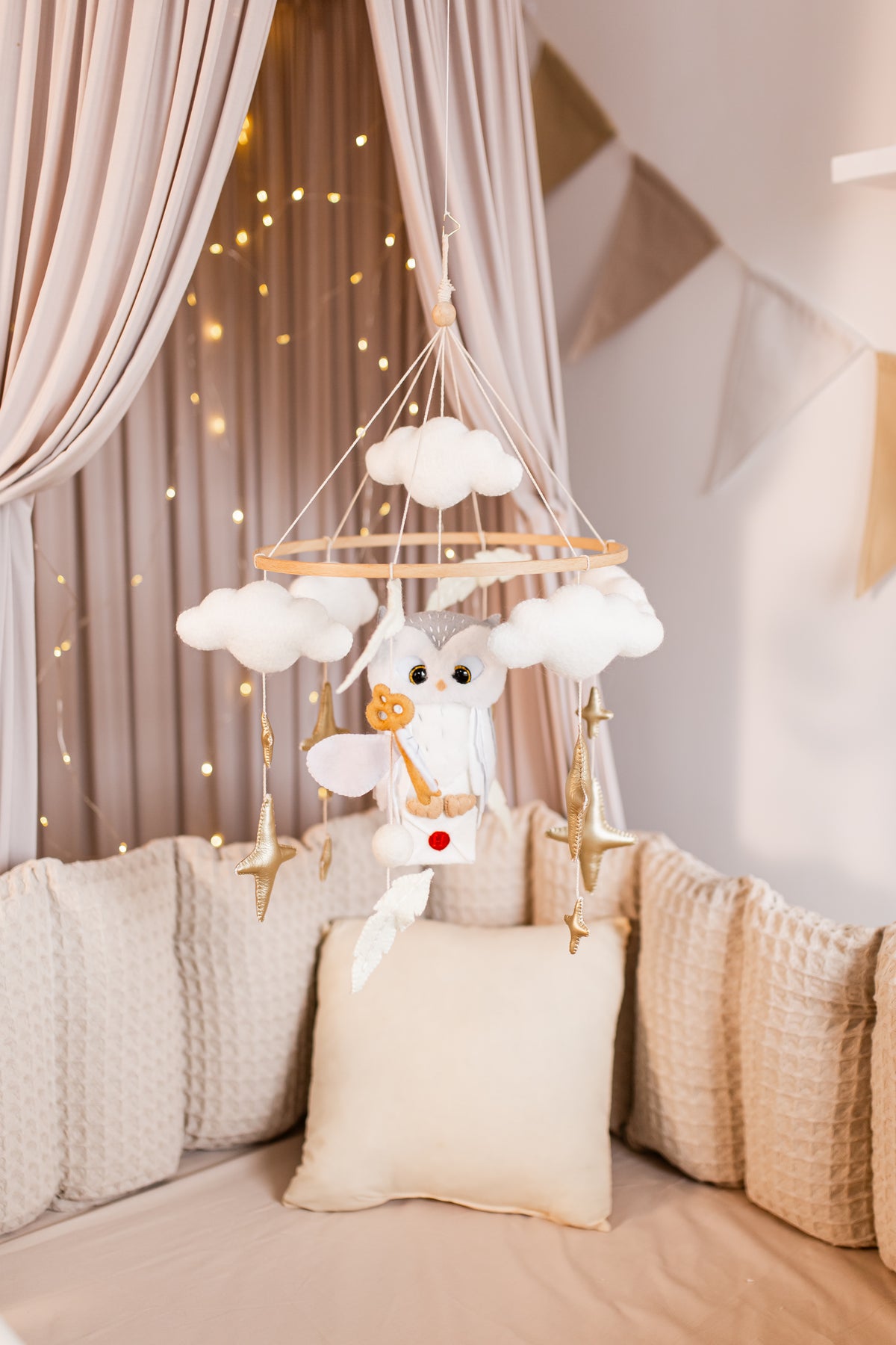 Baby crib mobile with plush toys and lights in a nursery setting