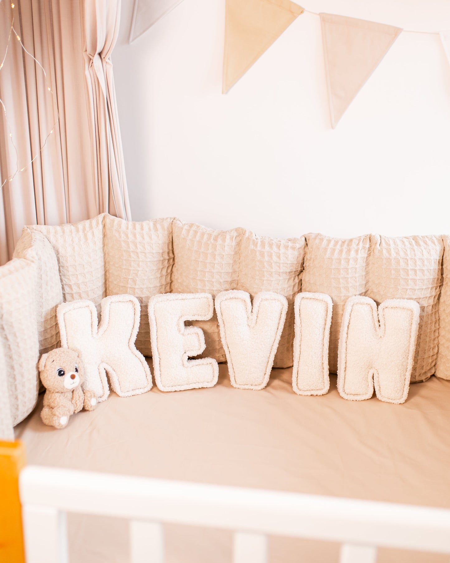 Personalized bouclé nursery decor displaying custom name with an animal teddy bear toy