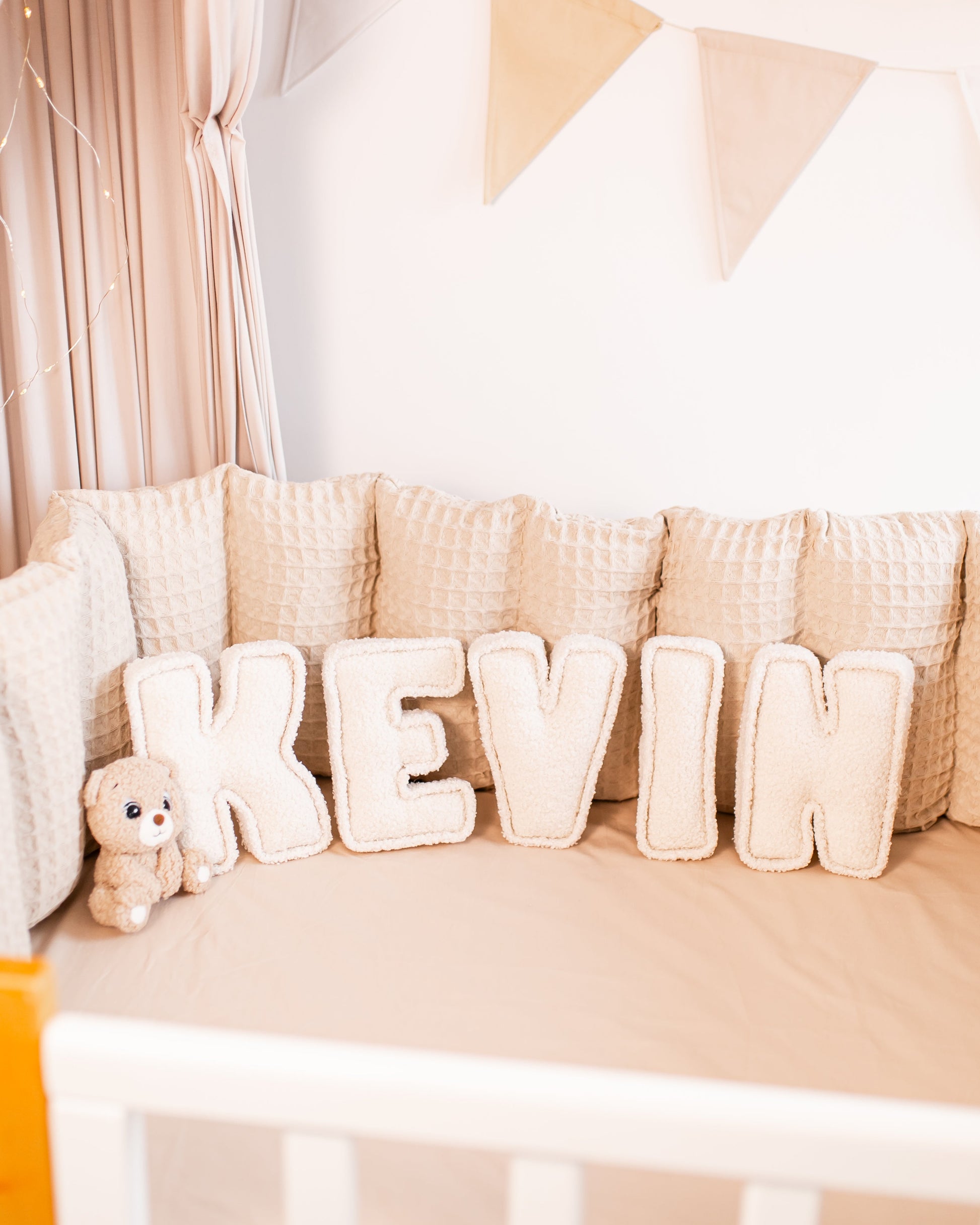 Personalized bouclé nursery decor displaying custom name with an animal teddy bear toy