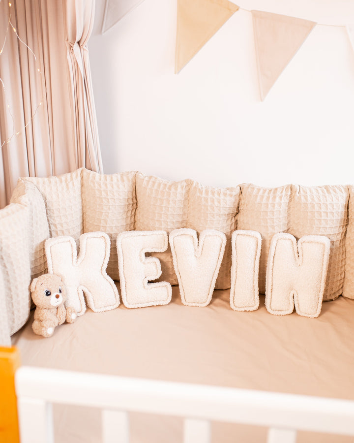 Personalized bouclé nursery decor displaying custom name with an animal teddy bear toy