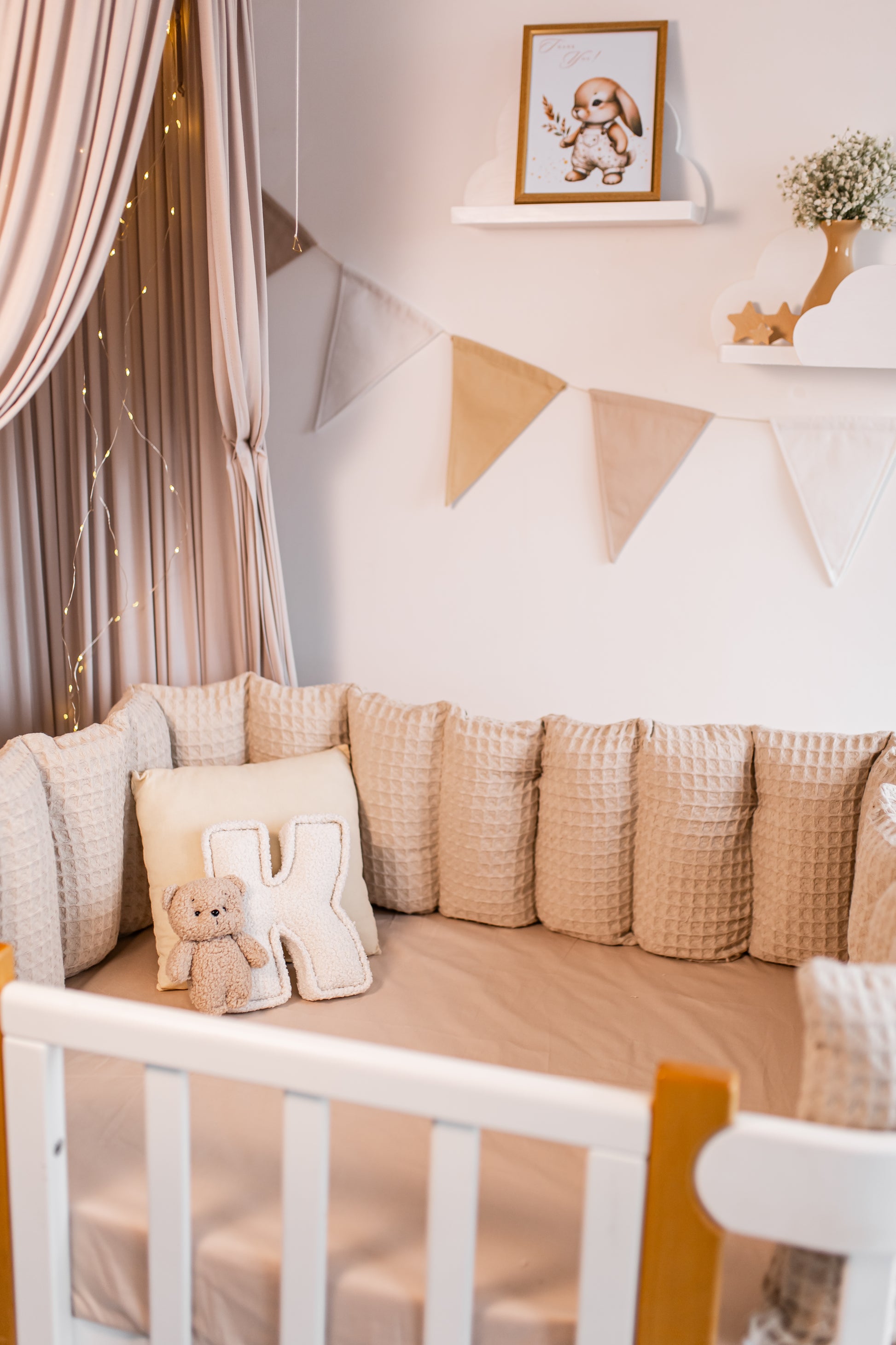 Nursery room with a crib, decorative letter pillows, and a teddy bear.