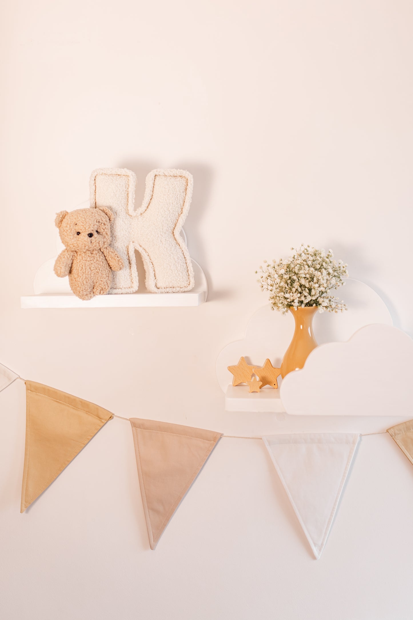 Decorative setup with a teddy bear, letter 'K', and bunting on a light background