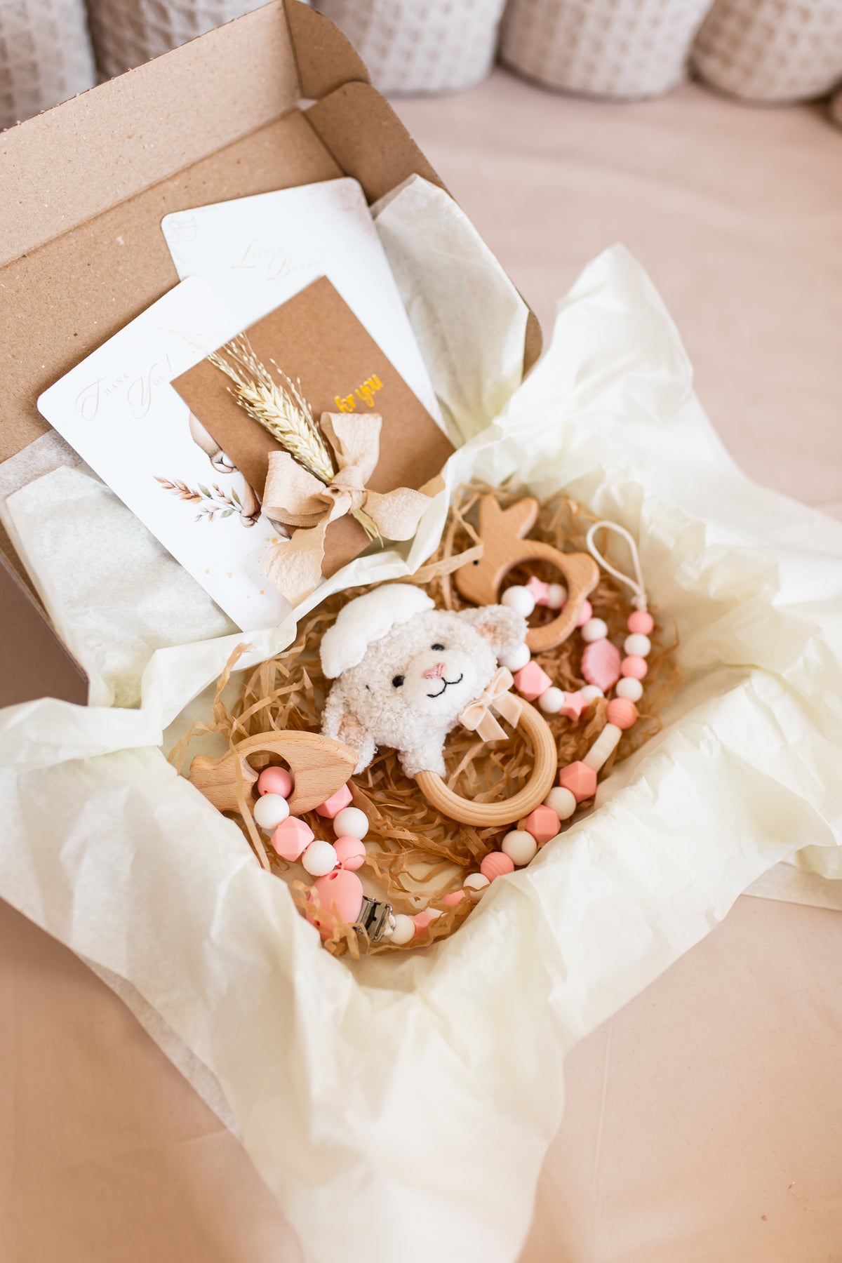 Baby teething ring with toys and cards in a box on a beige surface