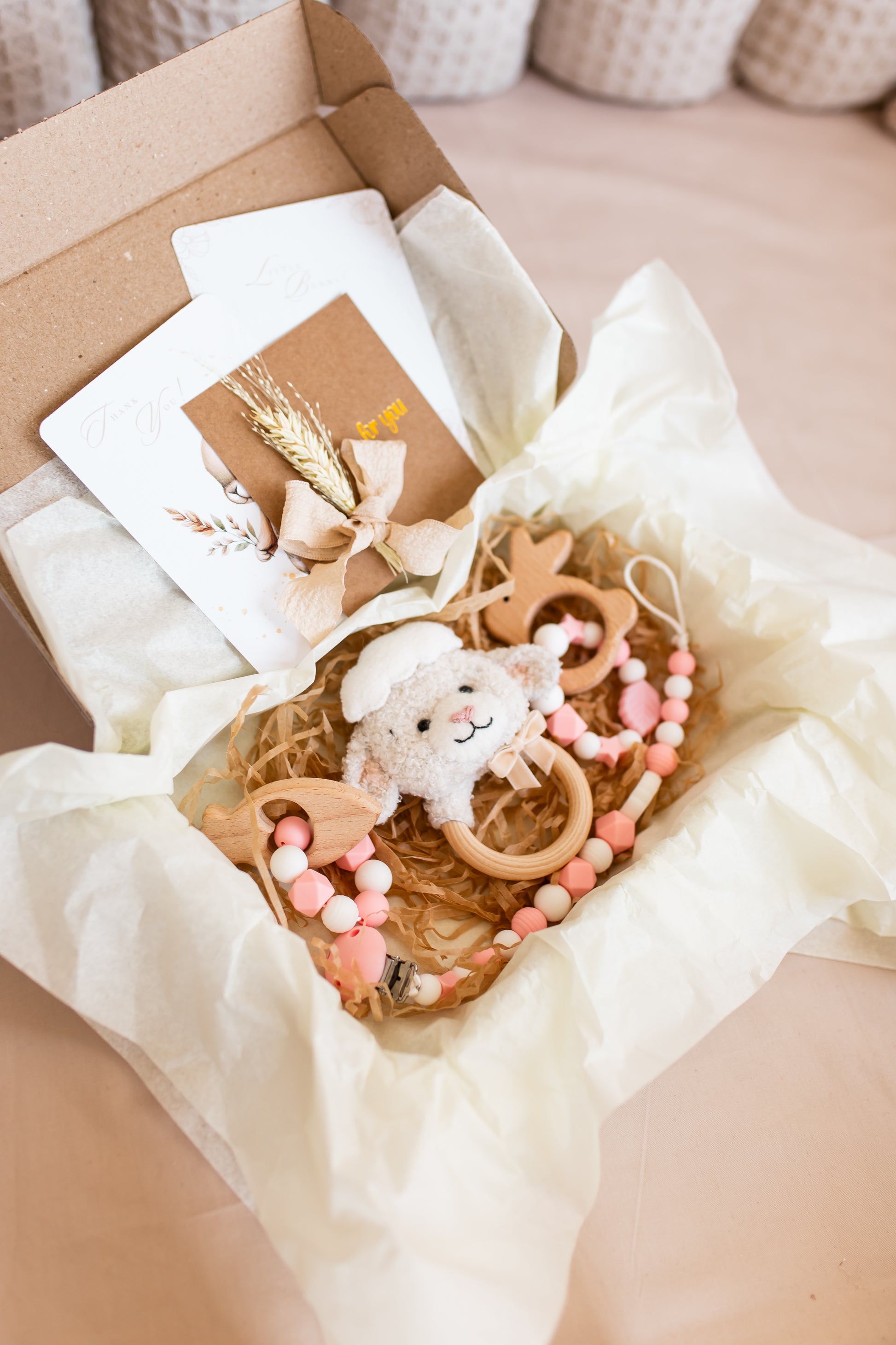 Baby teething ring with toys and cards in a box on a beige surface