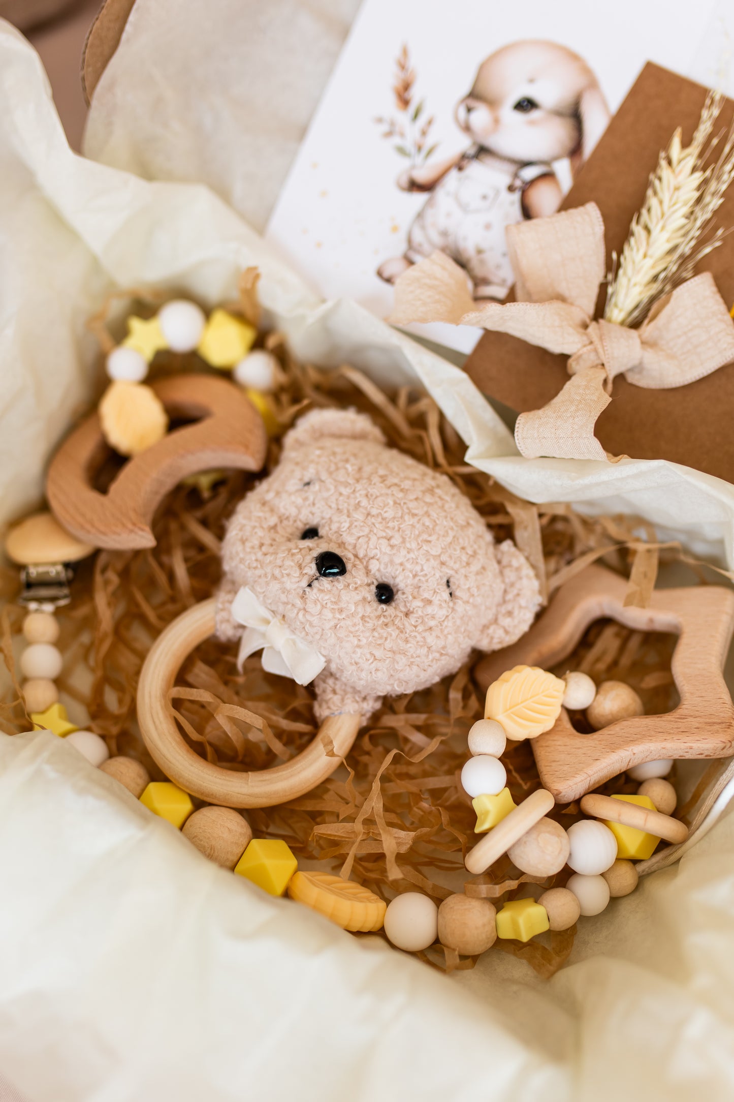 Baby toy set with a plush bear, wooden rings, and beads in a decorative box.