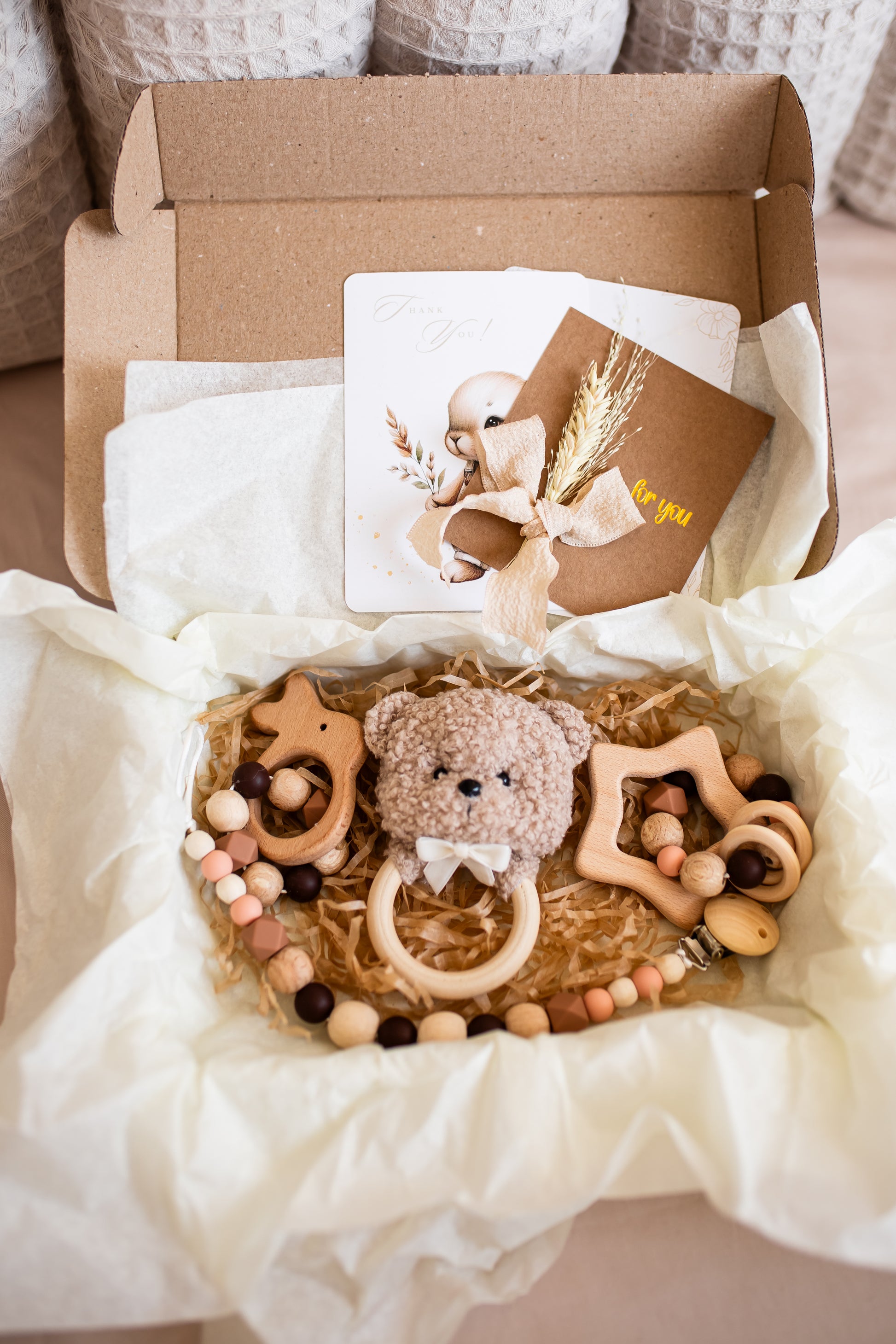 Baby gift set with teddy bear, teething ring, and card in a box